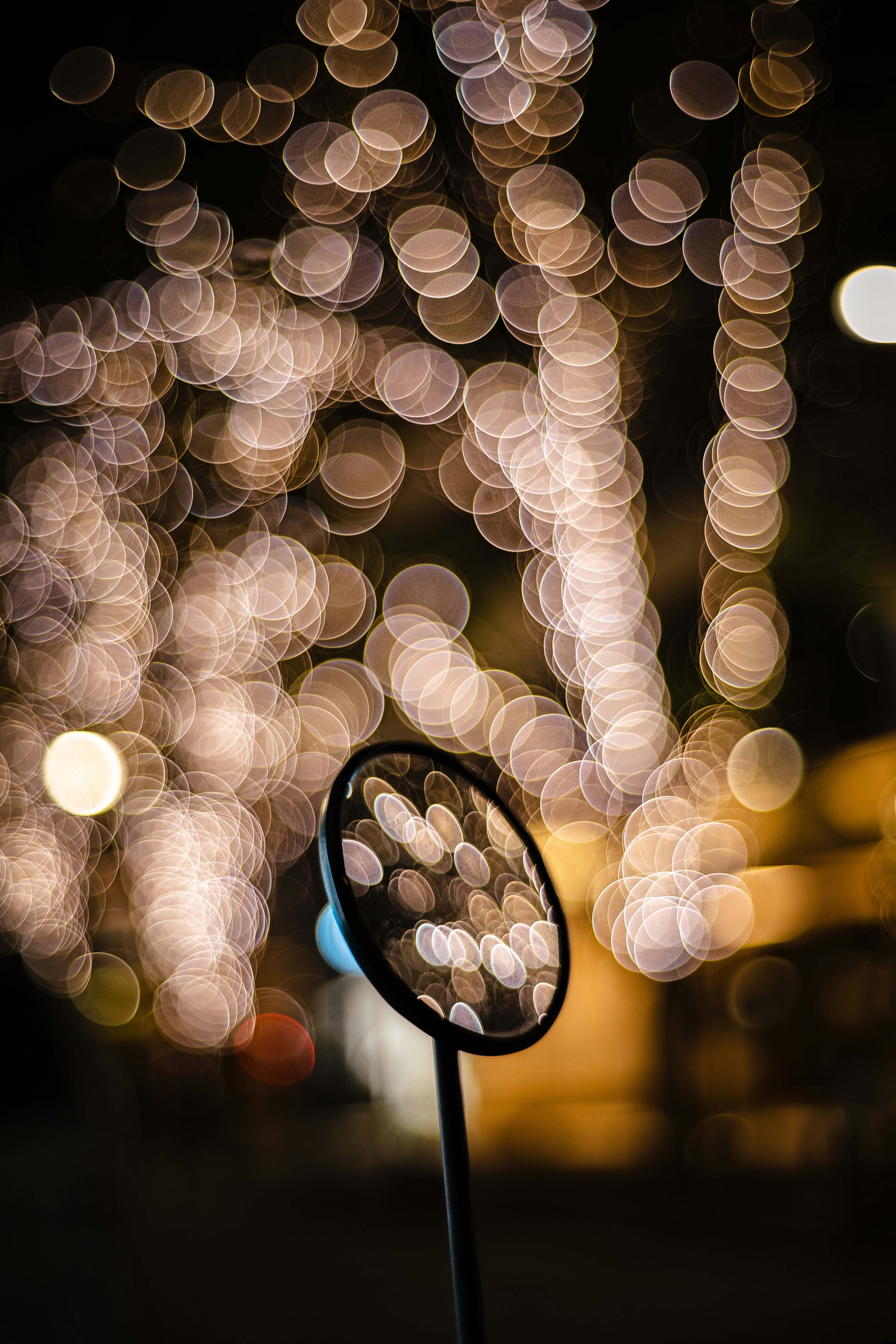 Objeto circular negro frente a un fondo borroso de luces cálidas