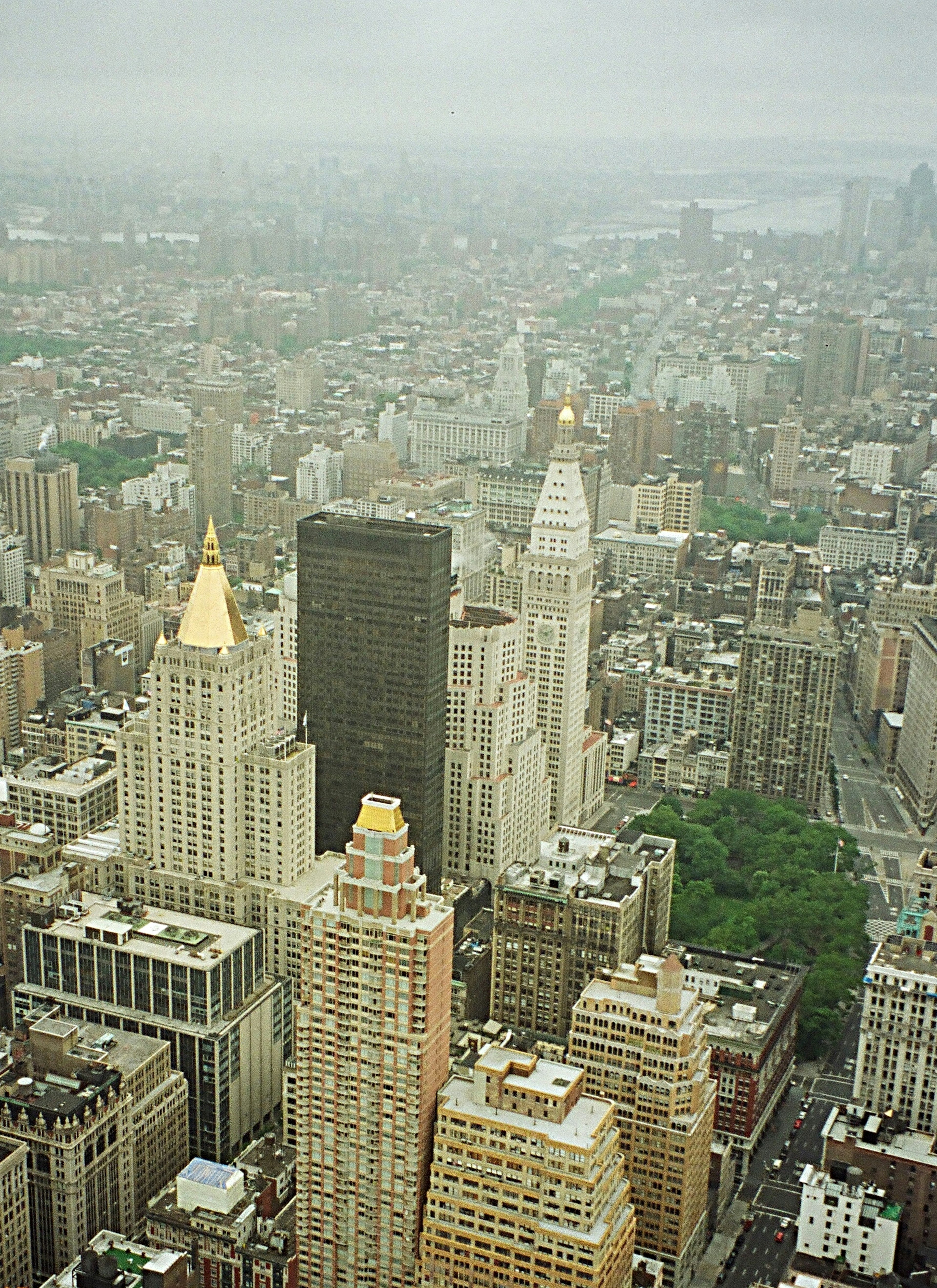 Aerial view of a foggy New York skyline featuring buildings with golden spires