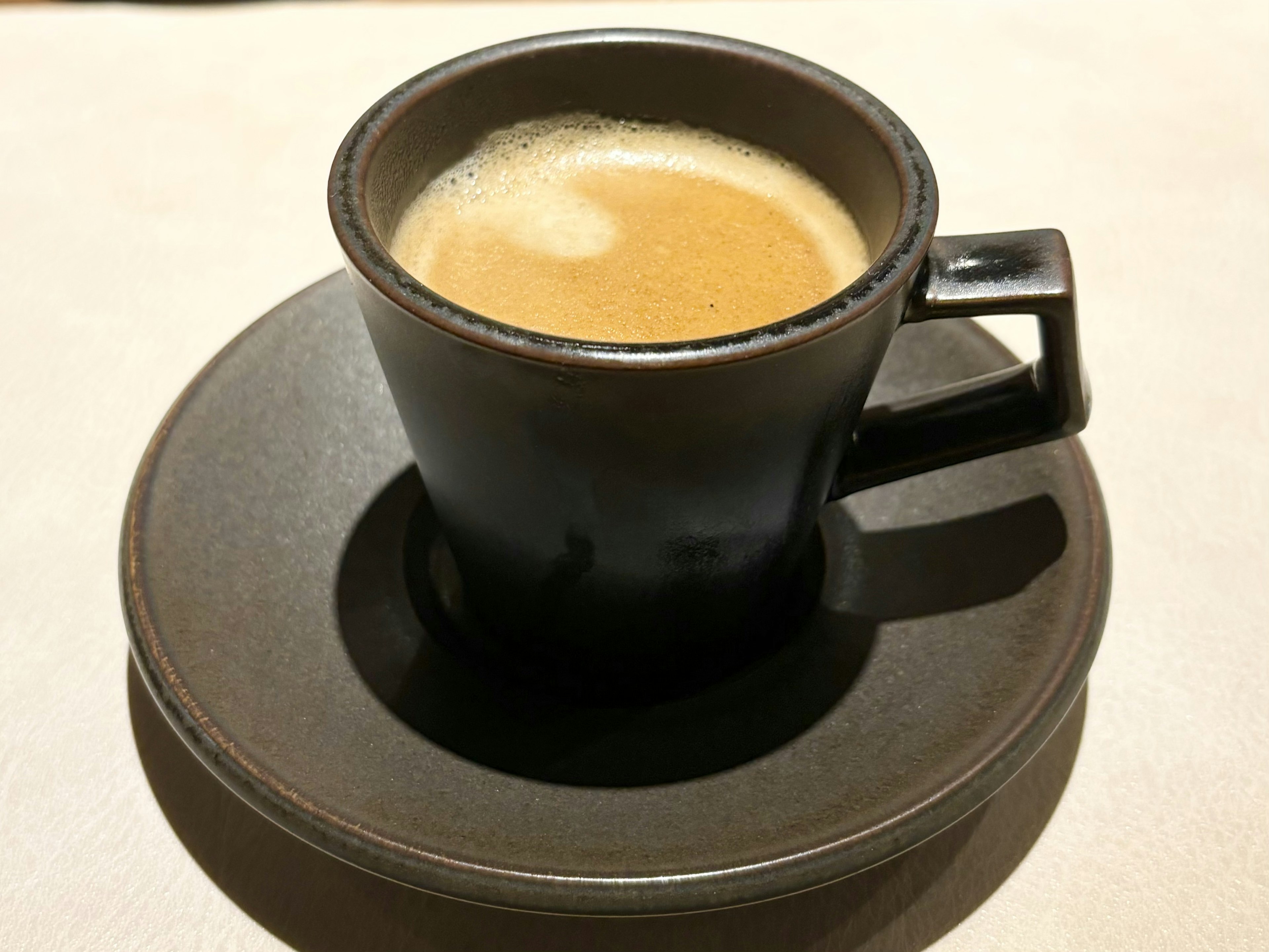 Espresso en una taza negra sobre un platillo a juego