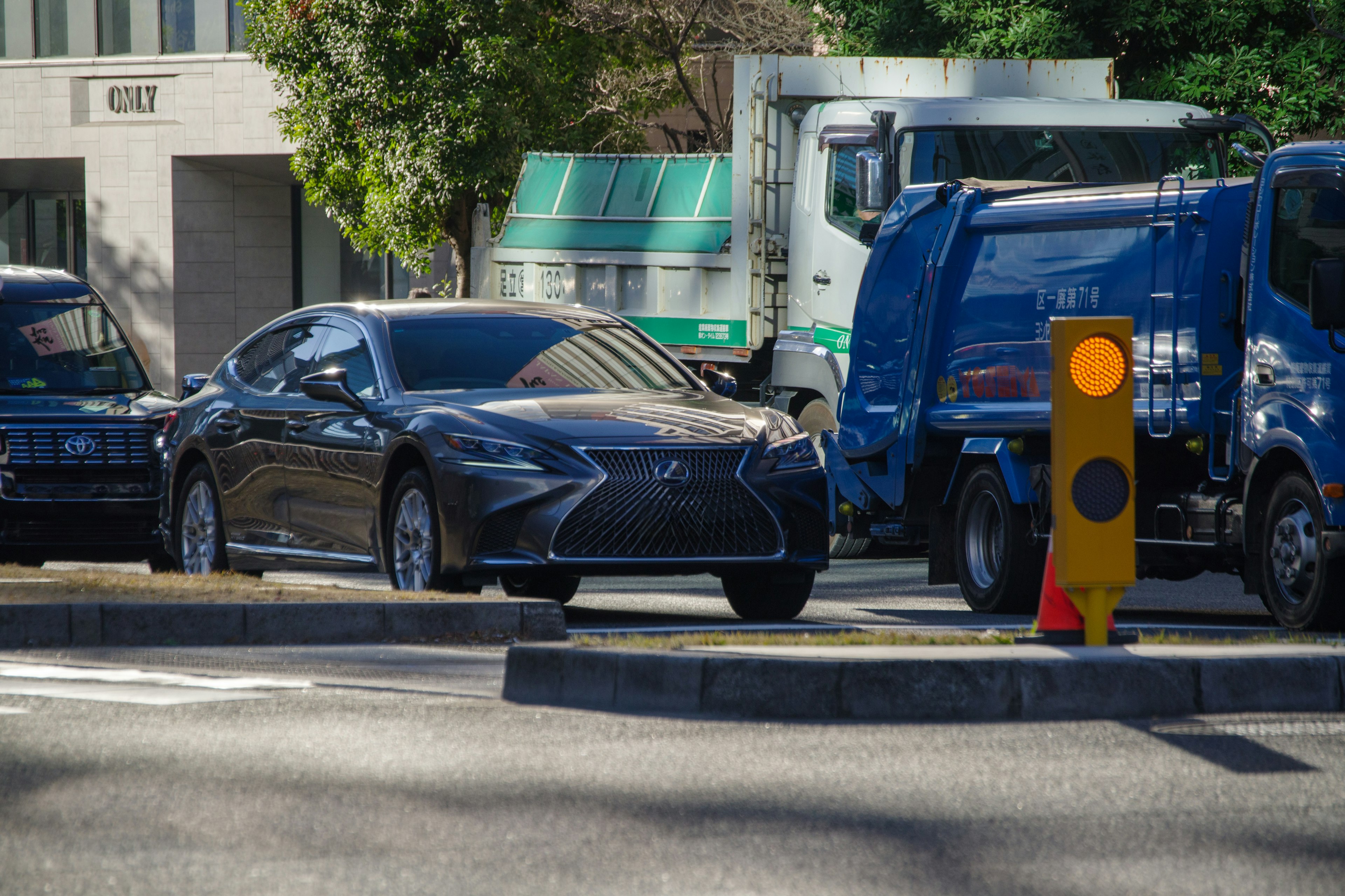 黒い高級車とトラックが並ぶ交差点の風景