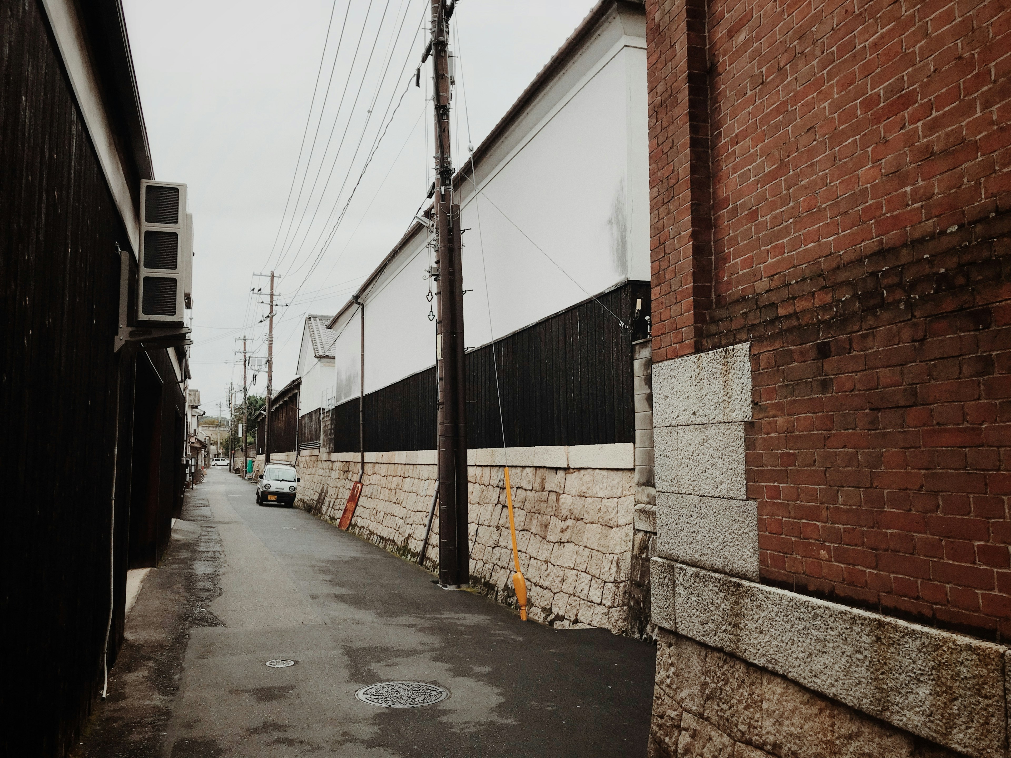 Narrow alley with black walls and red brick building