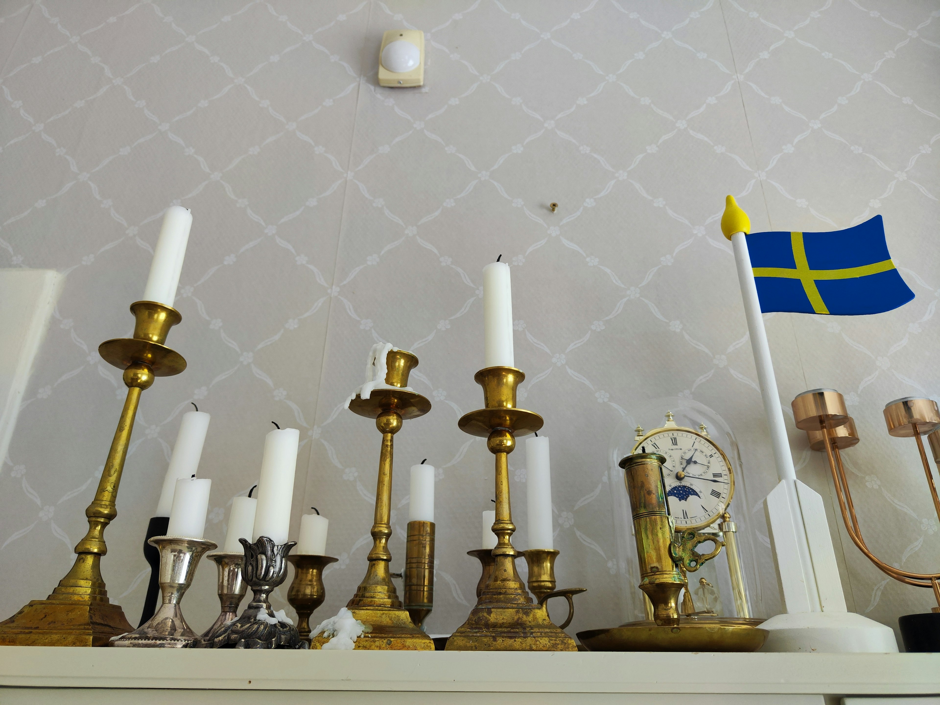 Swedish flag with various candle holders displayed on a shelf