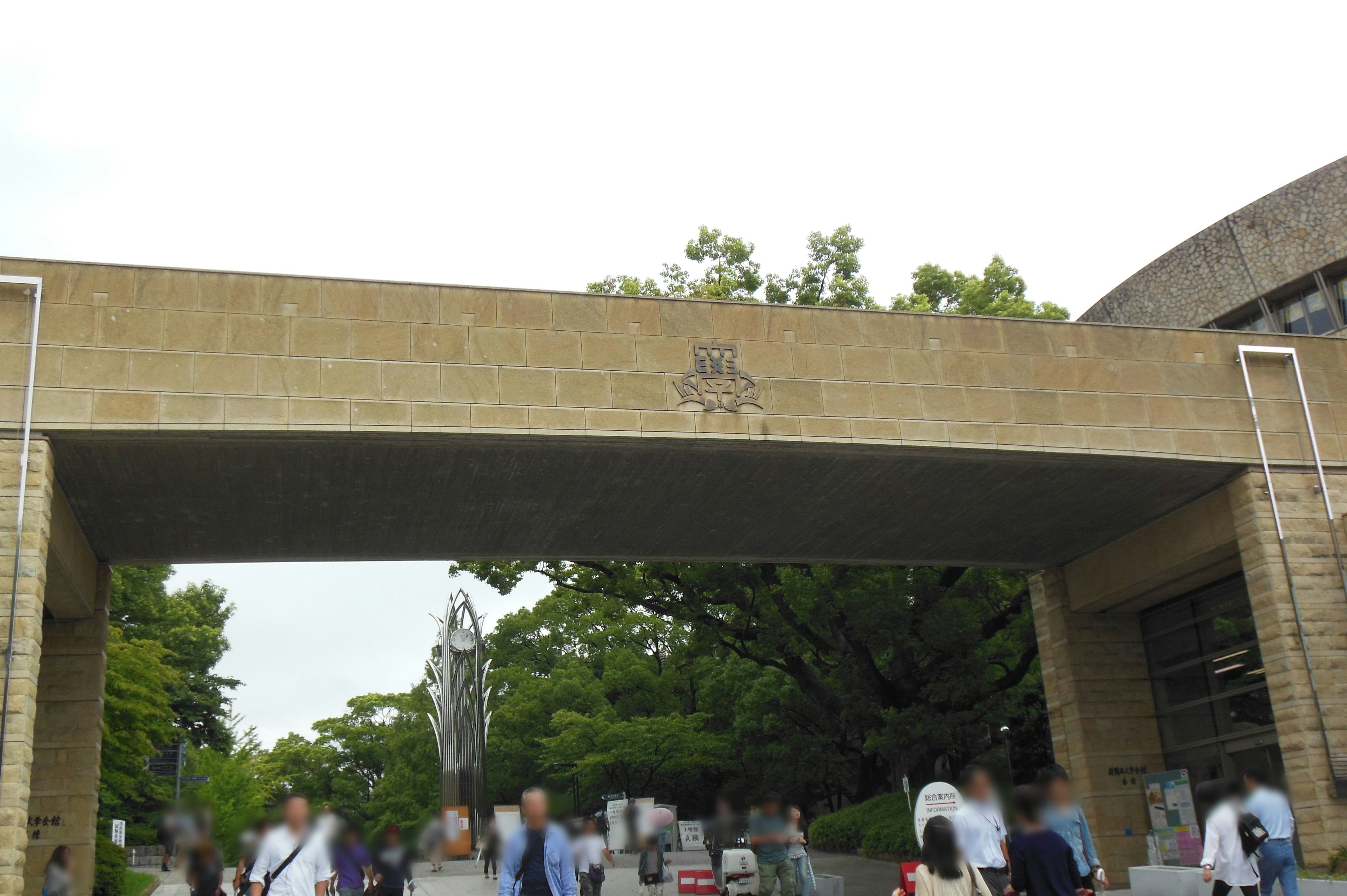 Scene of a bustling archway with people walking underneath surrounded by lush greenery