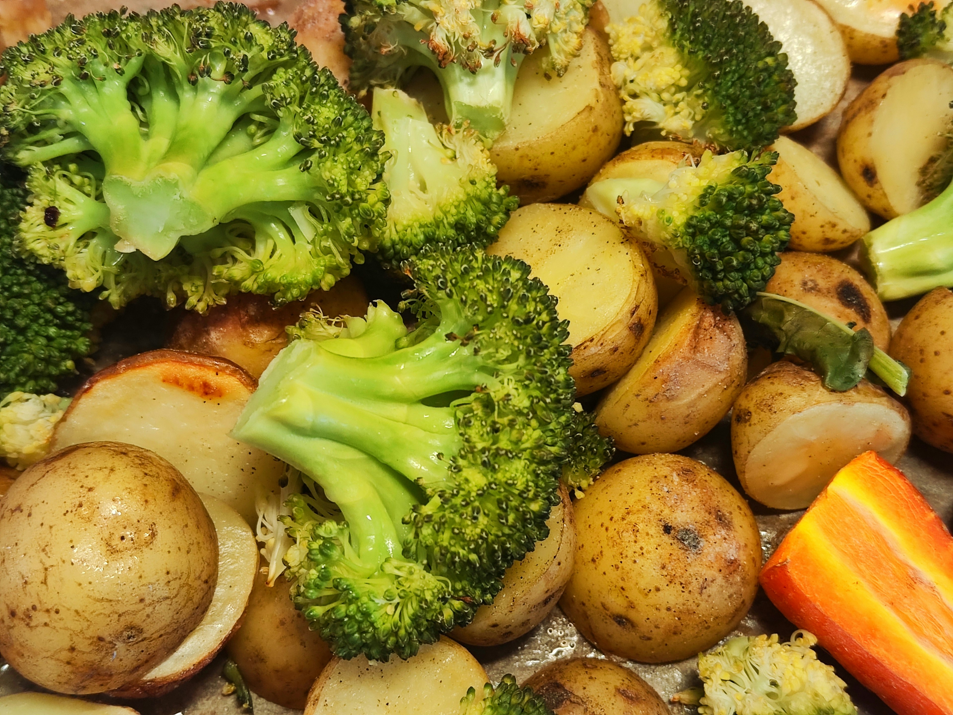 Primer plano de papas y brócoli asados en una mezcla de verduras