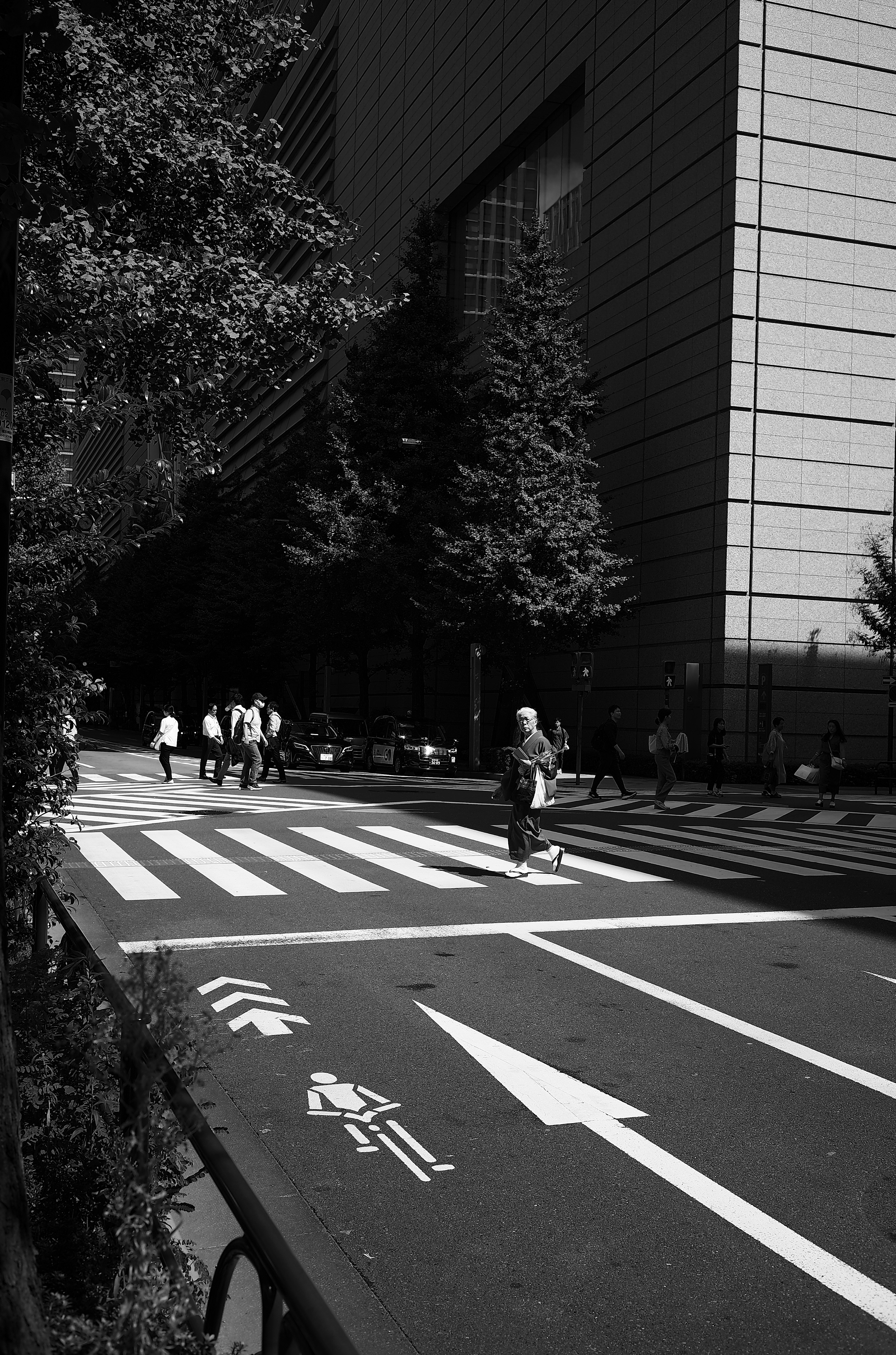 Peatones cruzando un paso de cebra en blanco y negro con rascacielos al fondo