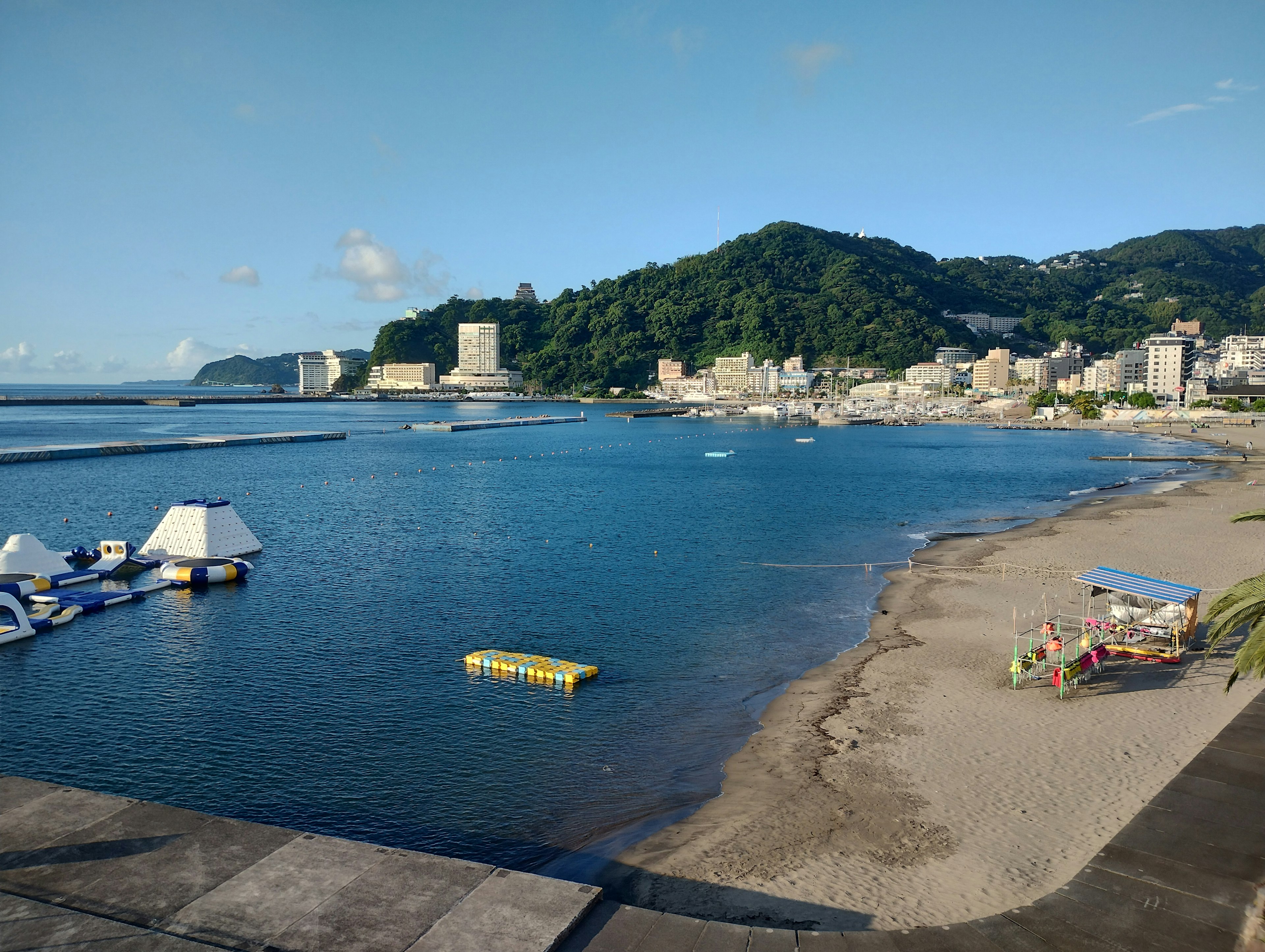 Scenic view of blue sea and sandy beach with boats and playground equipment