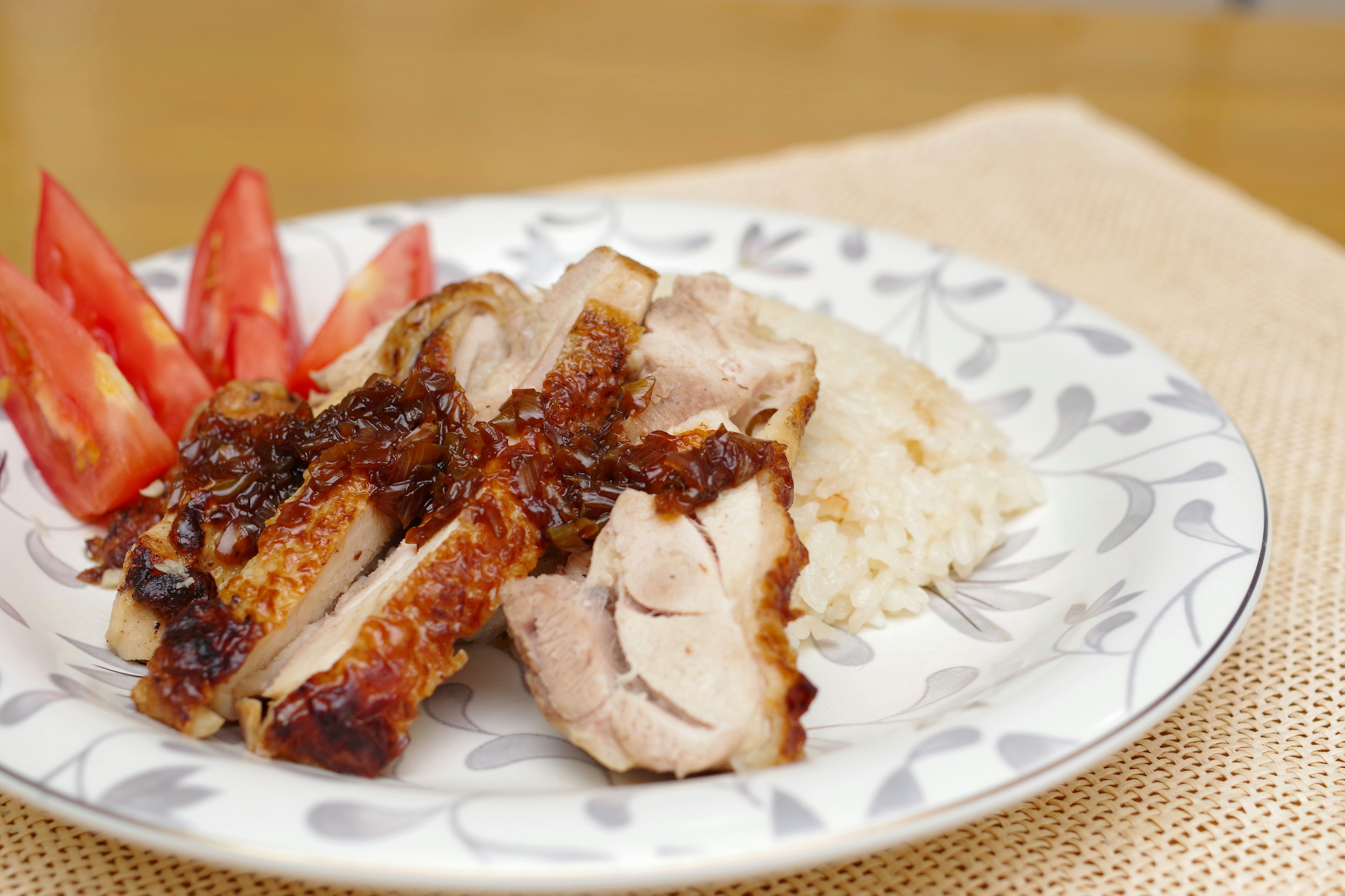 Piring lezat berisi ayam iris dengan nasi dan irisan tomat