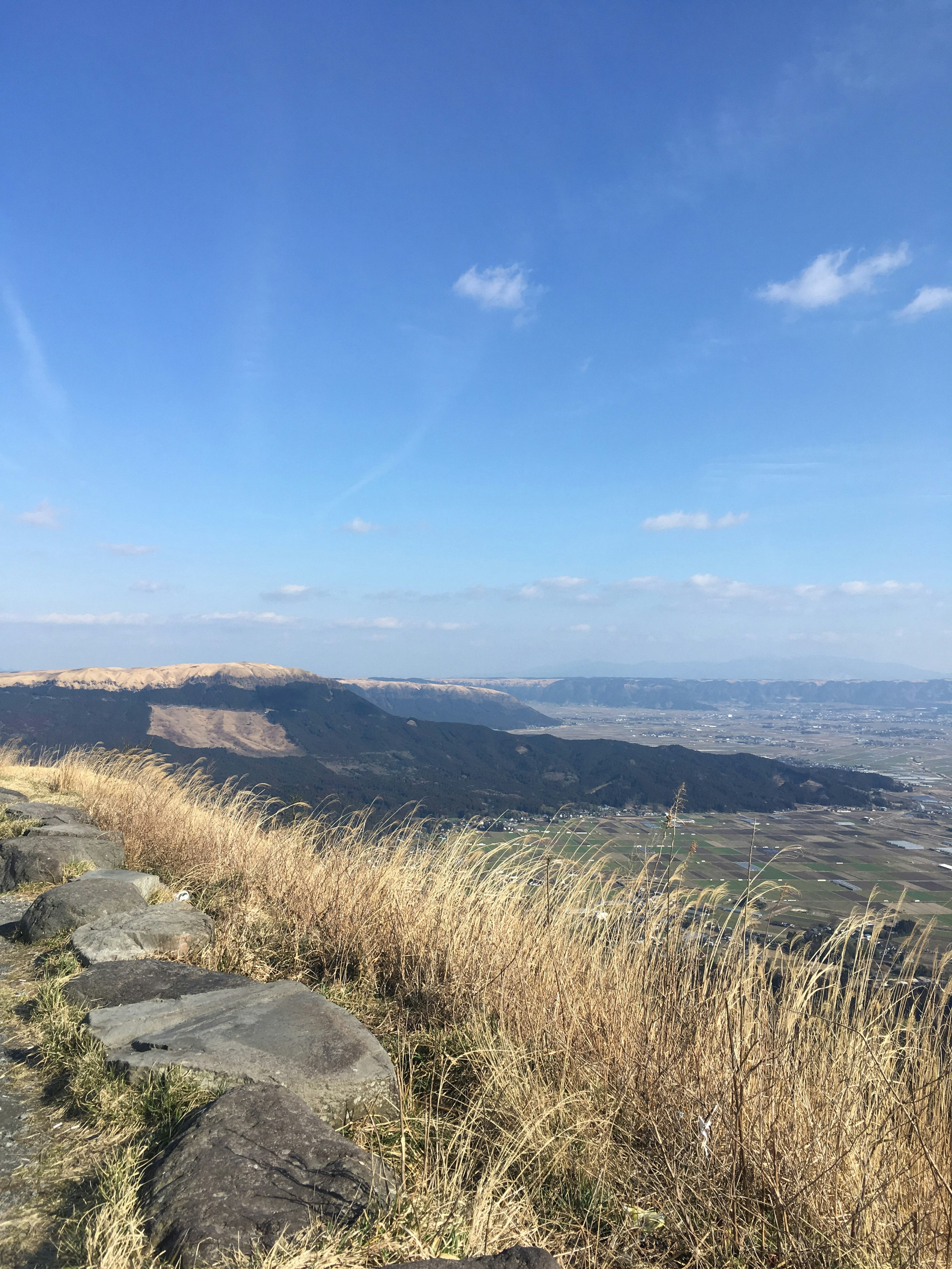 Ampia vista di colline erbose e montagne lontane sotto un cielo blu