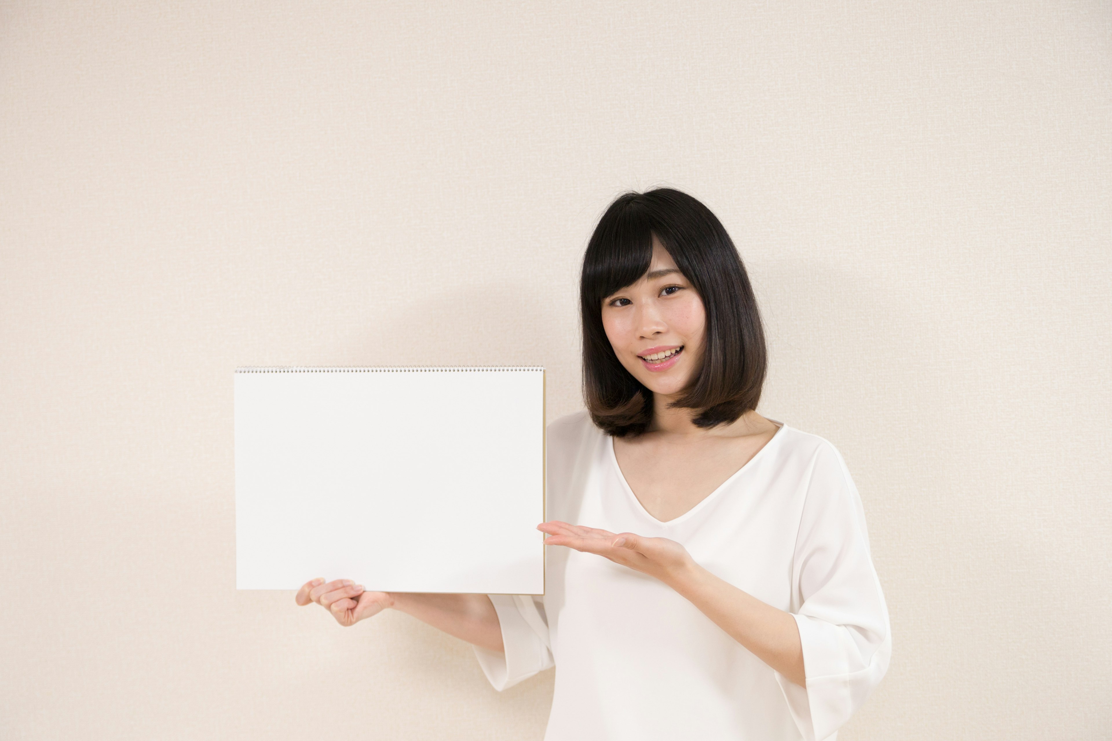 Woman holding a blank white board against a light background