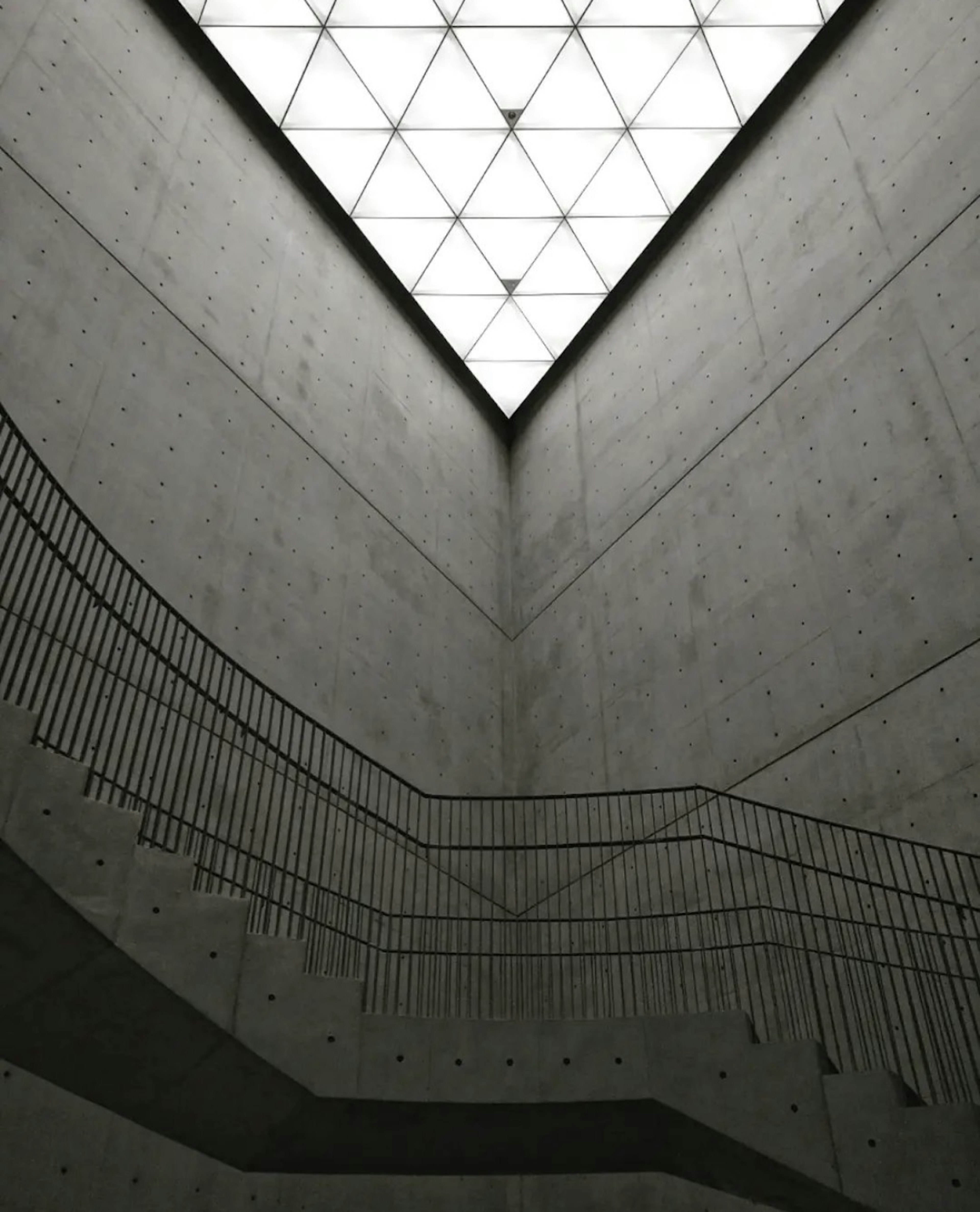 Modern architectural space with concrete walls and staircase featuring a lit ceiling