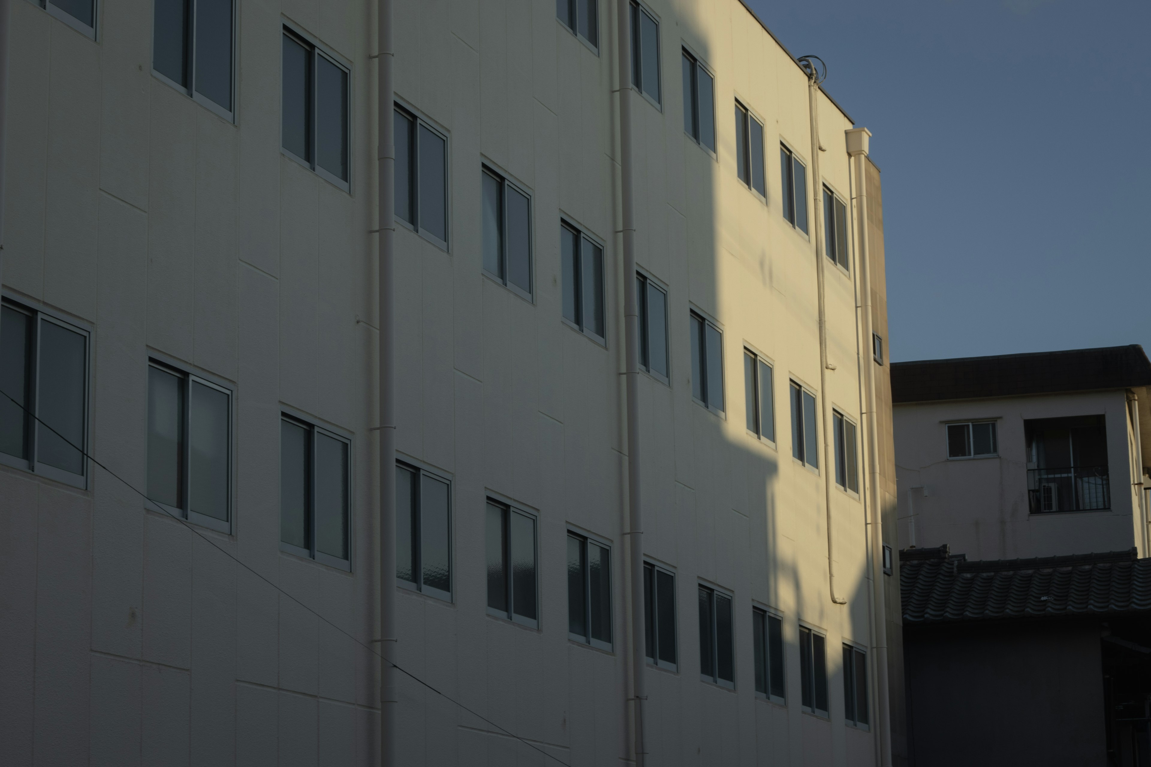 Schatten und Fensterstruktur an der Gebäudefassade bei Dämmerung