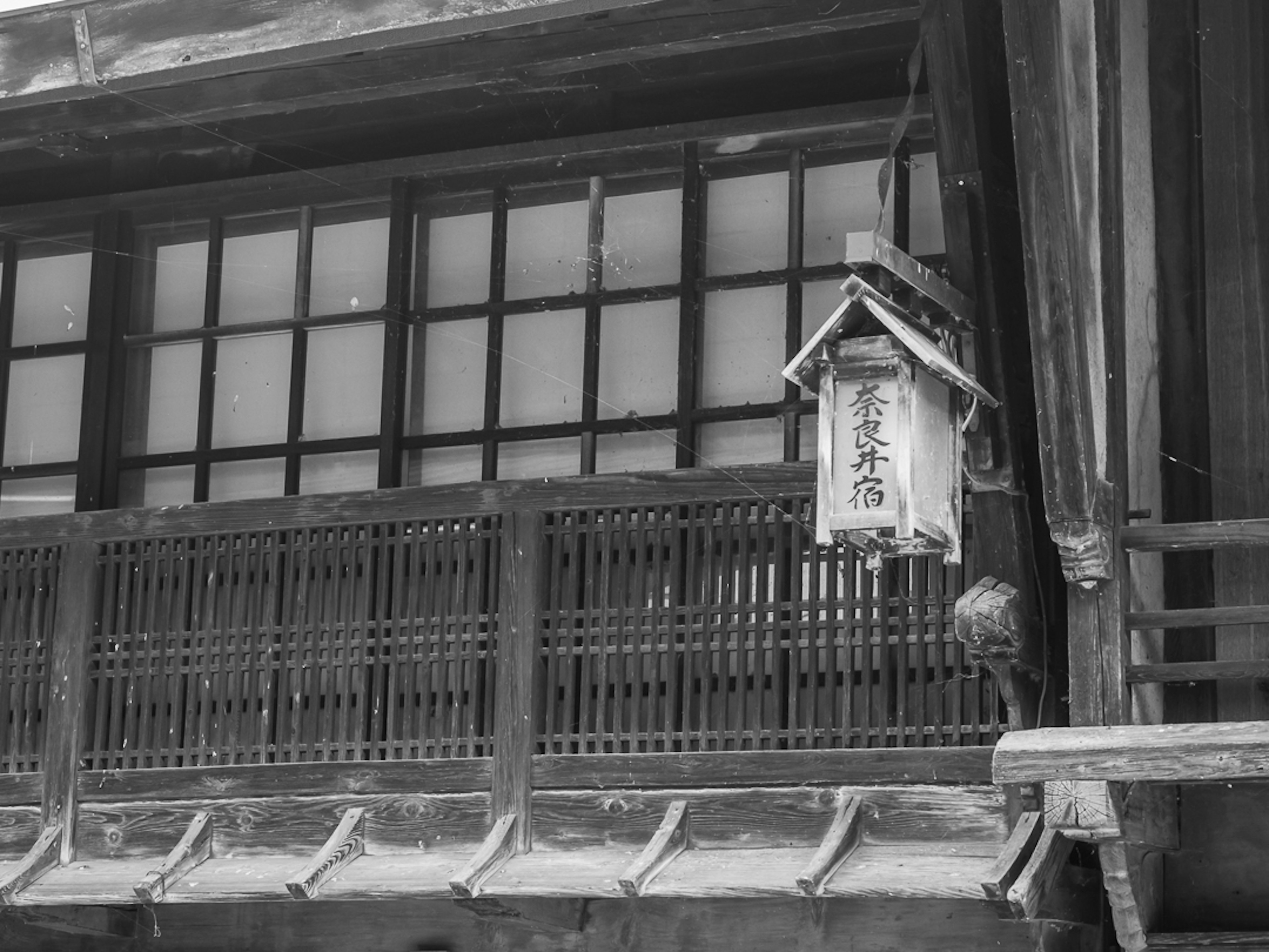 Traditionelle japanische Laterne, die an einem Balkon eines alten Holzgebäudes hängt