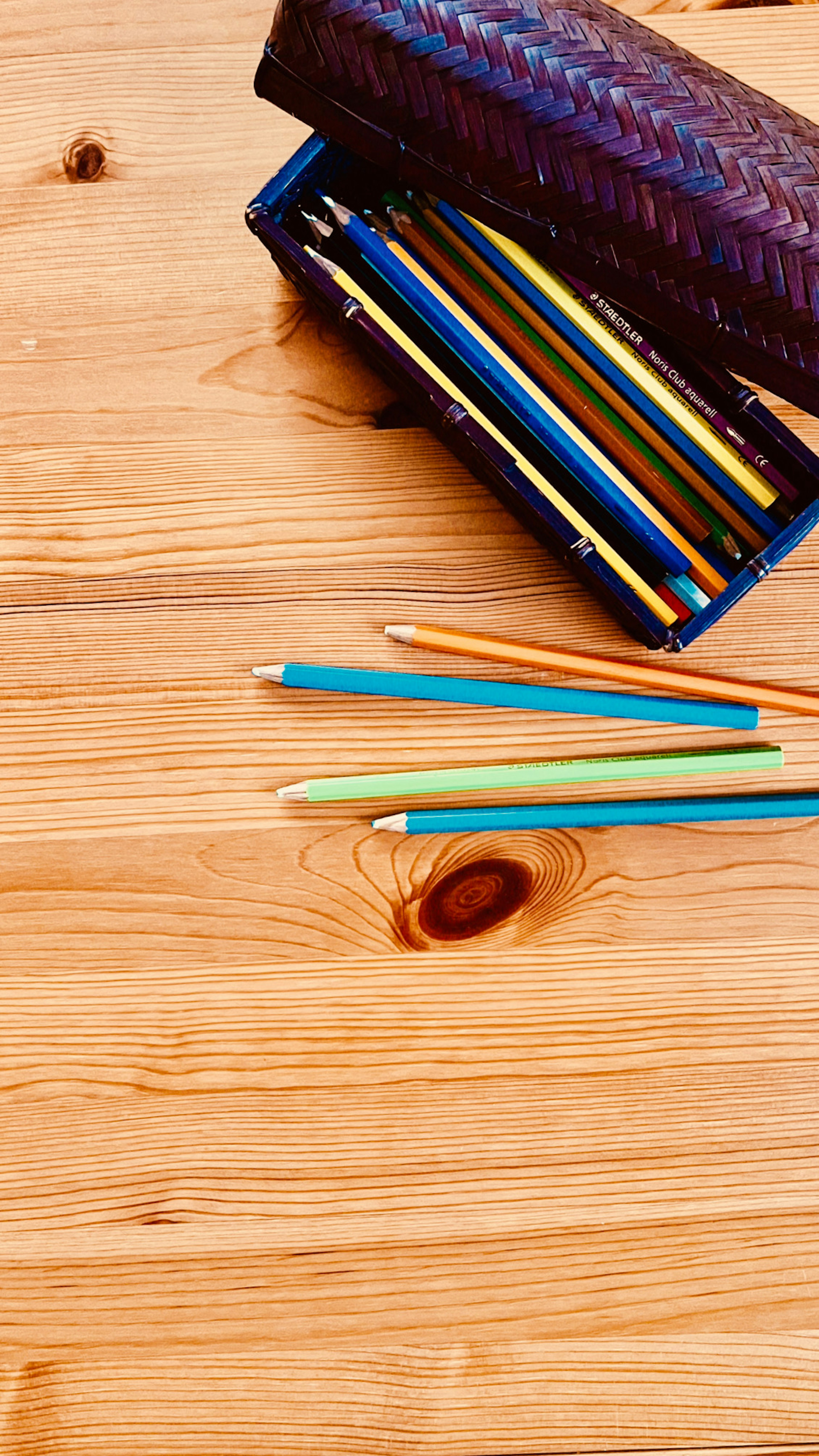 Lápices de colores y un estuche sobre una mesa de madera