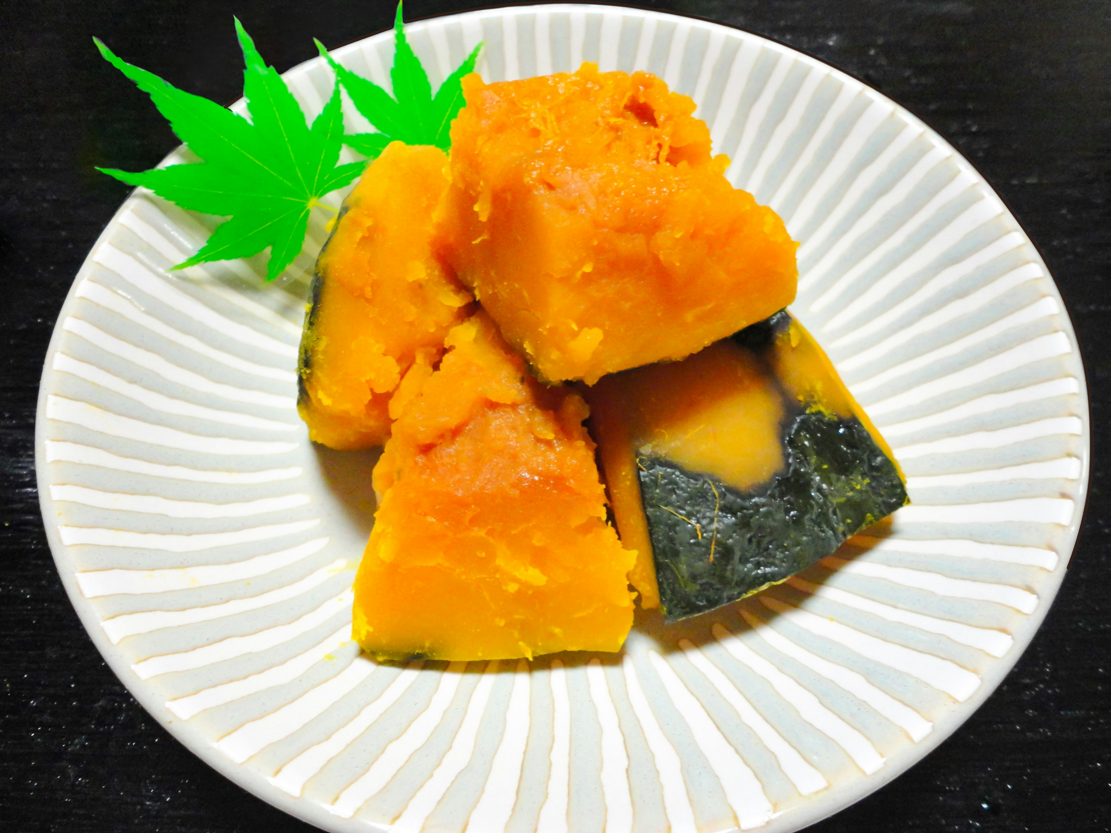 Piezas de calabaza al vapor en un plato decorativo con guarnición verde