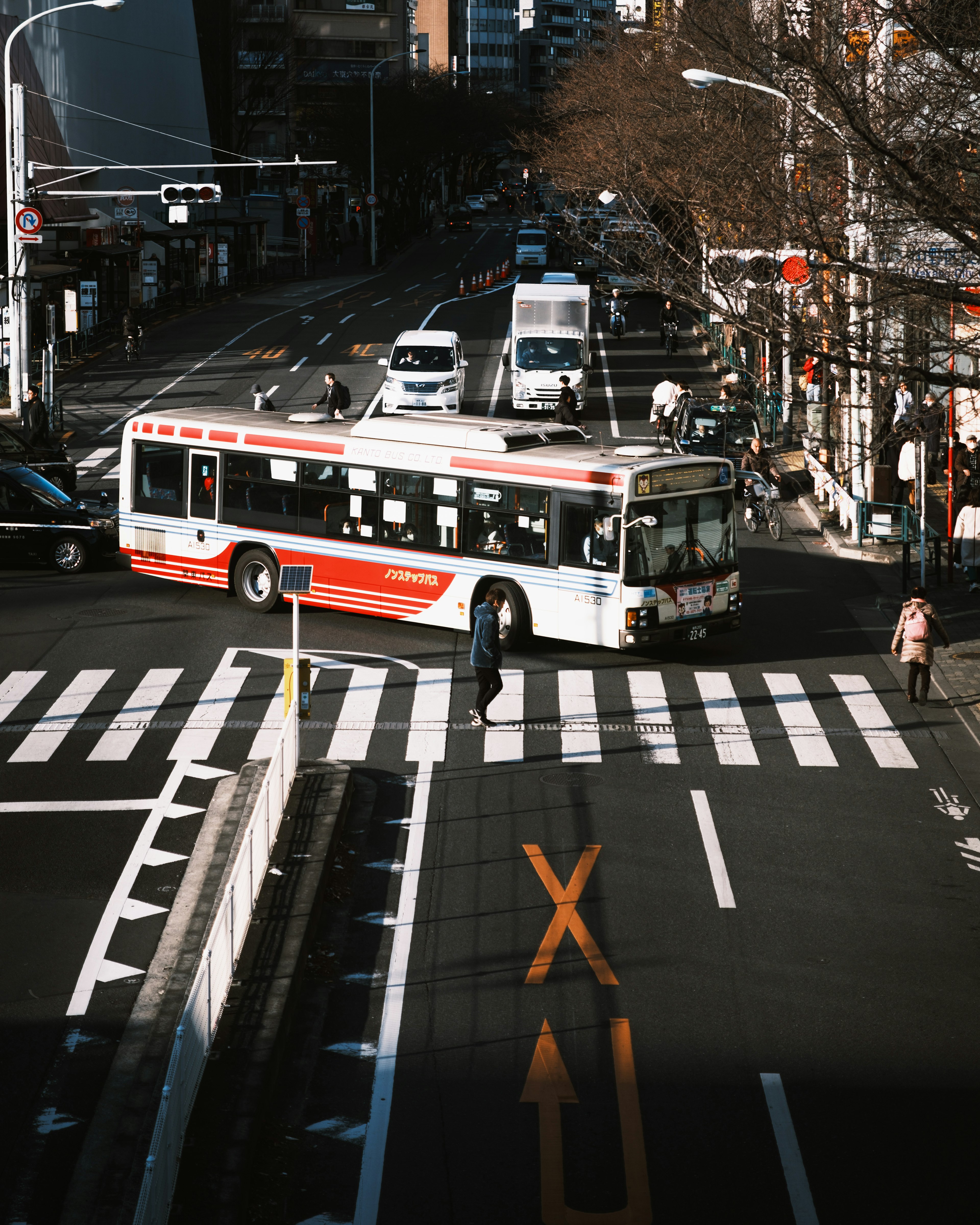 City scene with a red-striped bus turning at an intersection