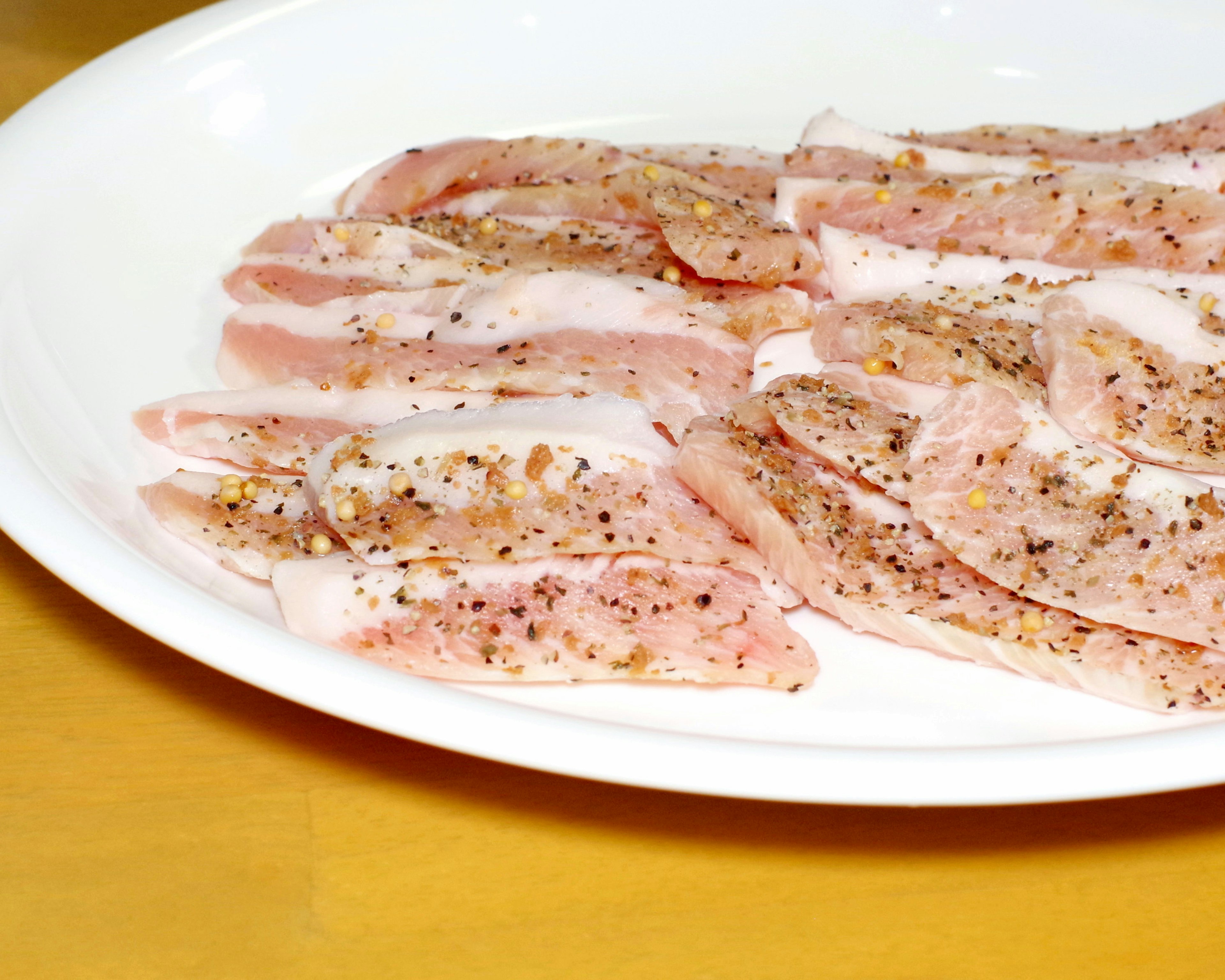 Carne en rodajas finamente sazonada dispuesta en un plato blanco