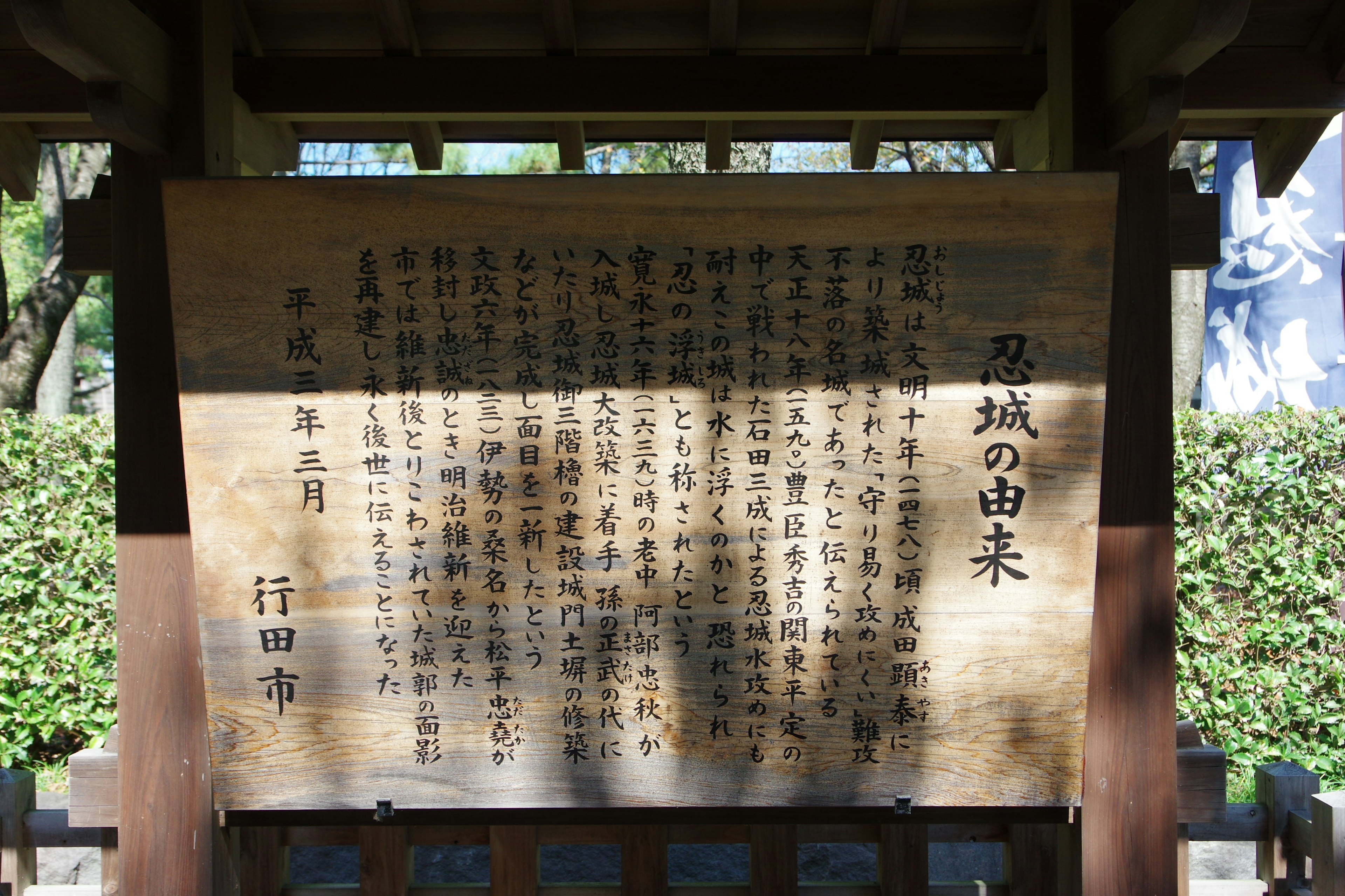 木製の看板に日本語の文字が書かれた説明文がある風景