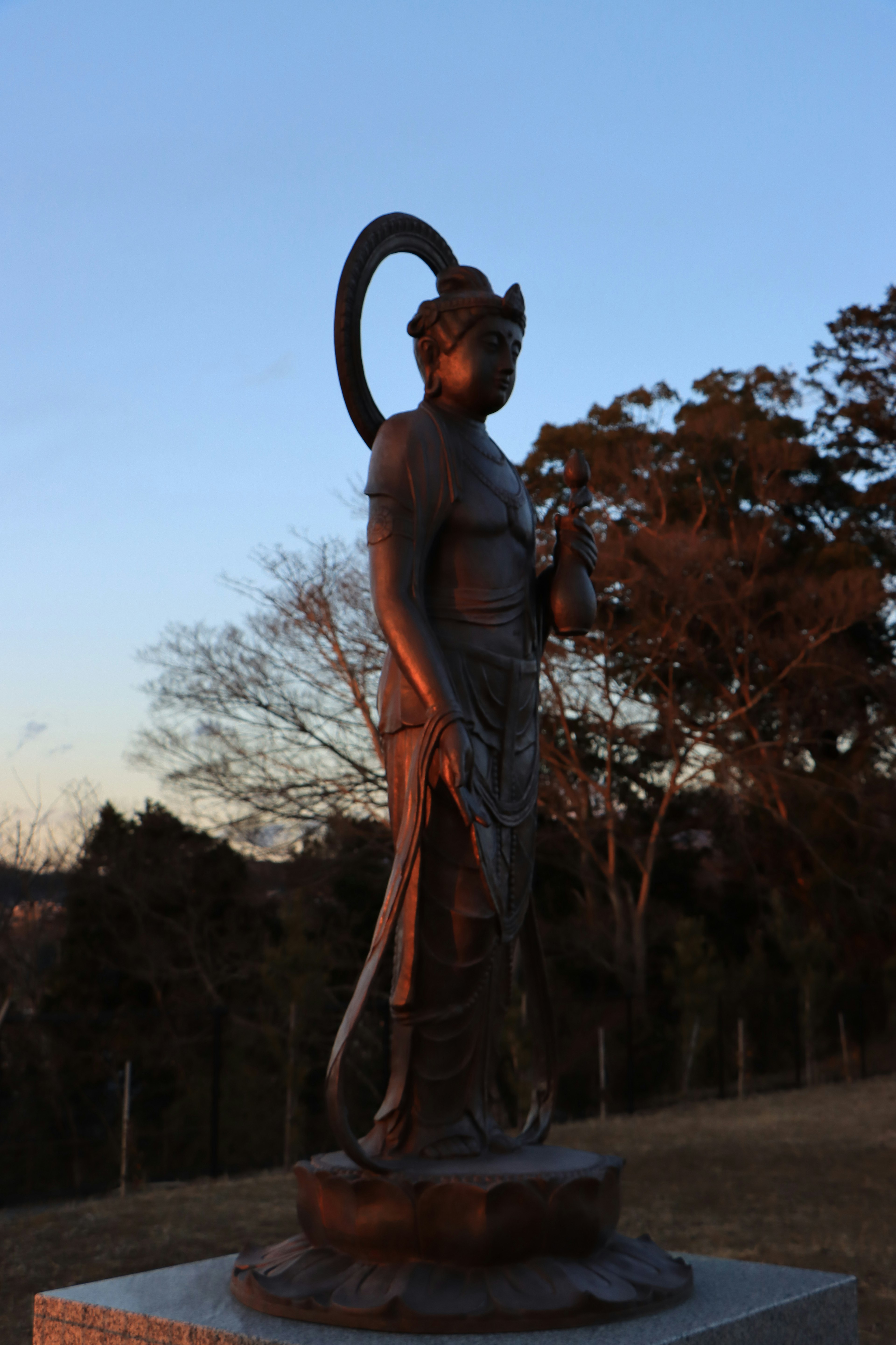 Statue in der Dämmerung mit Bäumen im Hintergrund