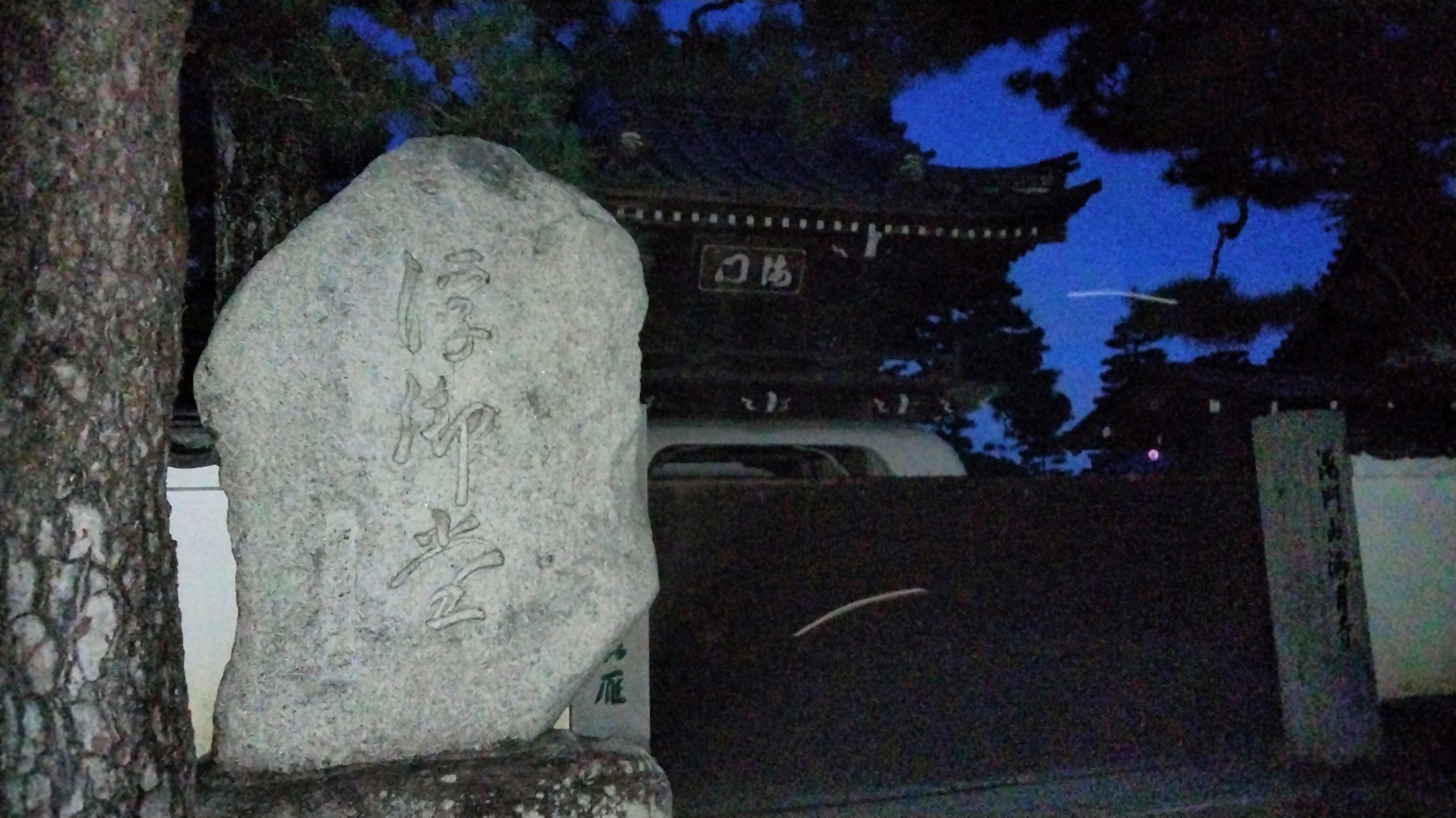 夜の寺院の門と大きな石碑の風景