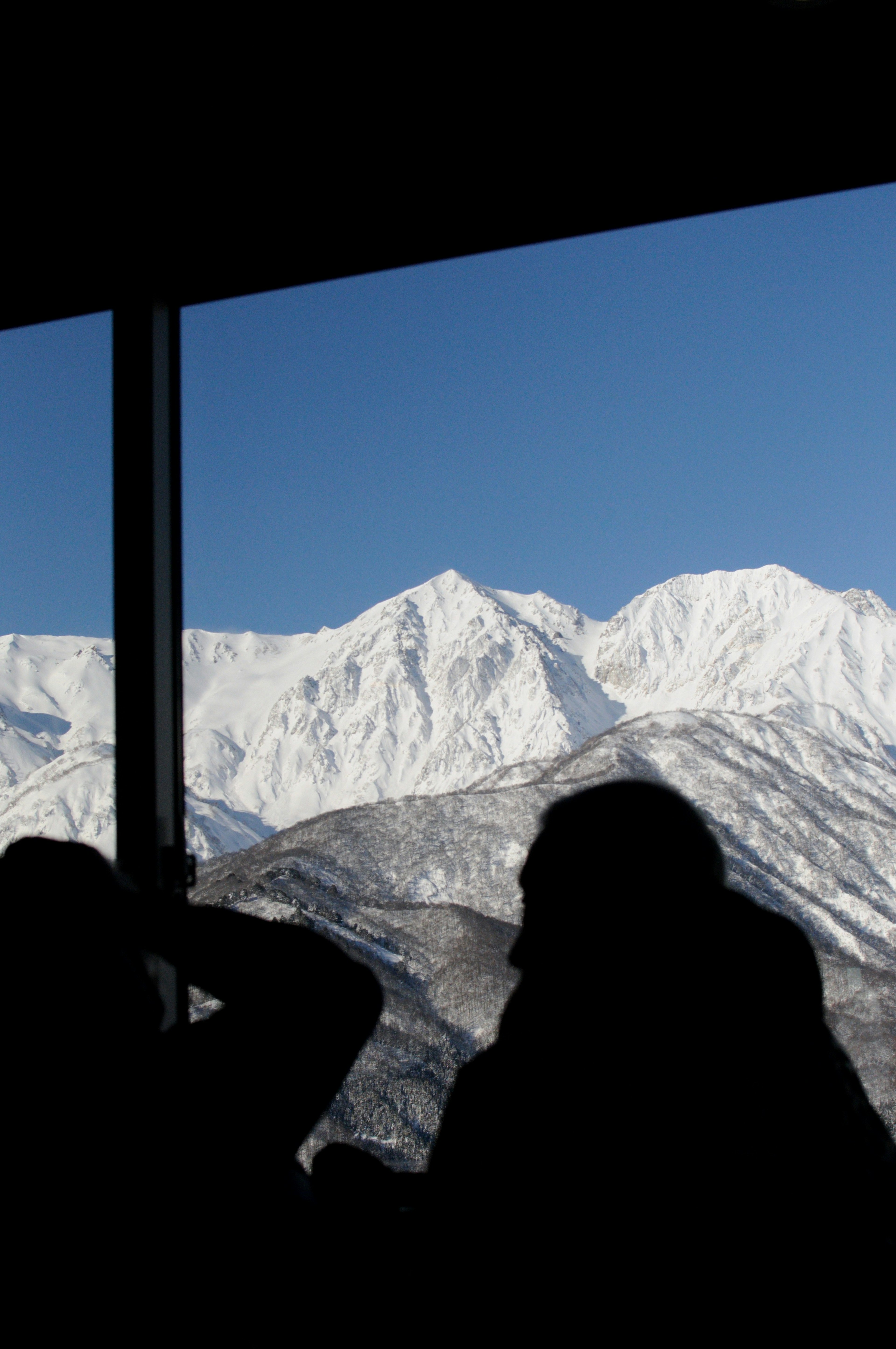 雪に覆われた山々を背景にしたシルエットの人々