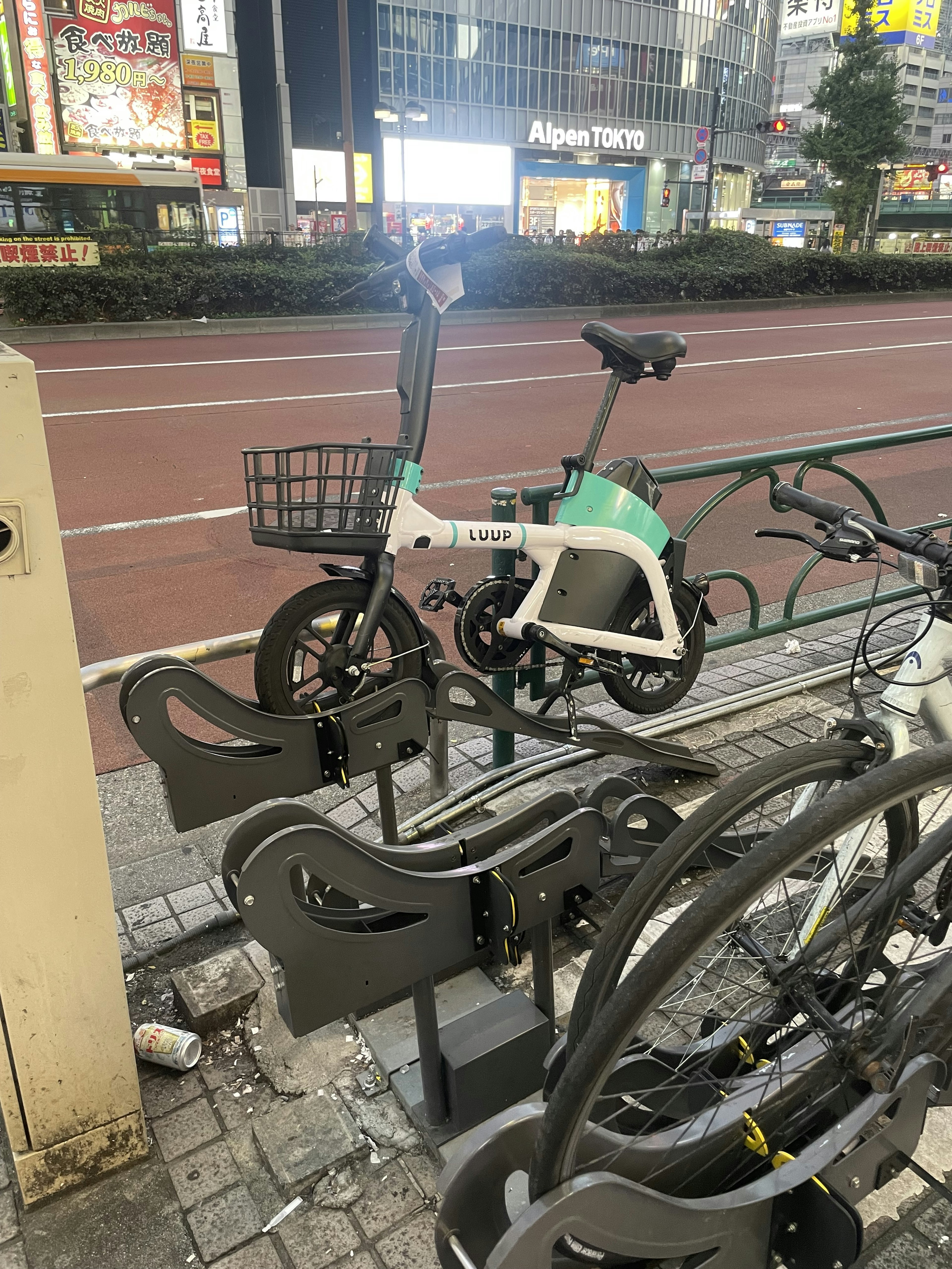 Bicicletta elettrica compatta parcheggiata in una stazione di noleggio in una strada cittadina di notte