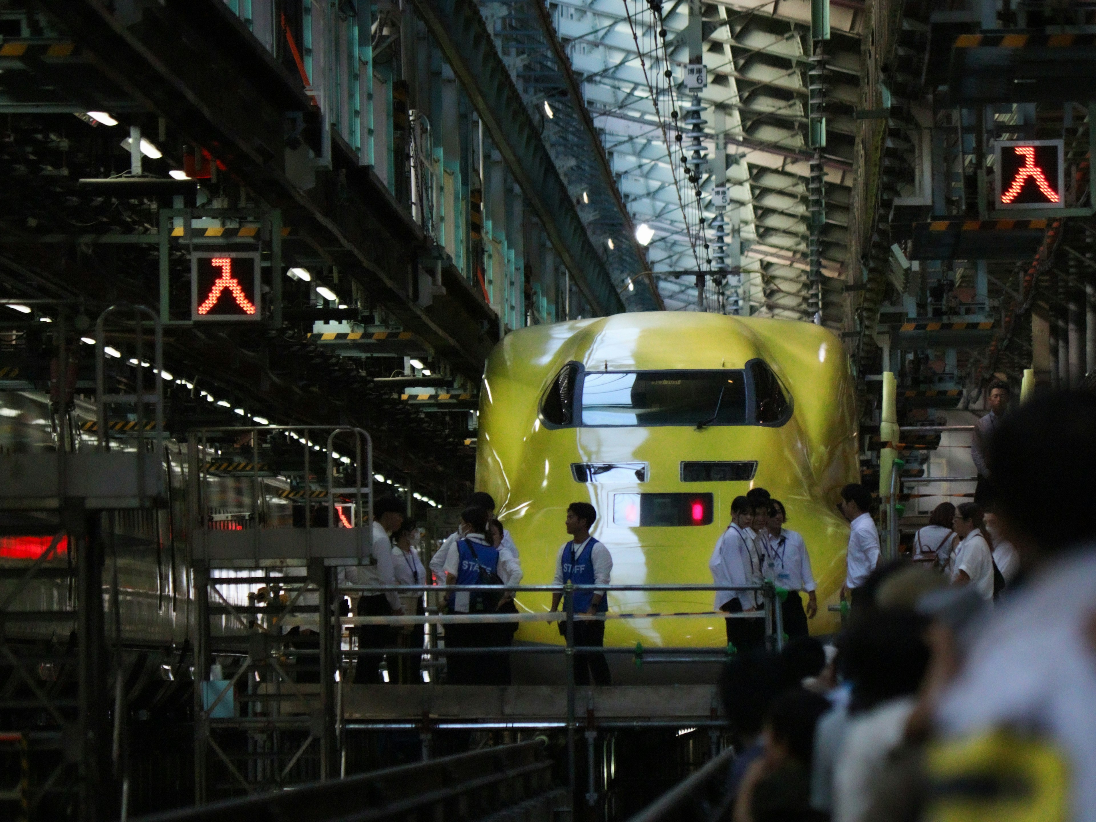 Sebuah kereta Shinkansen kuning sedang diperiksa di dalam pabrik