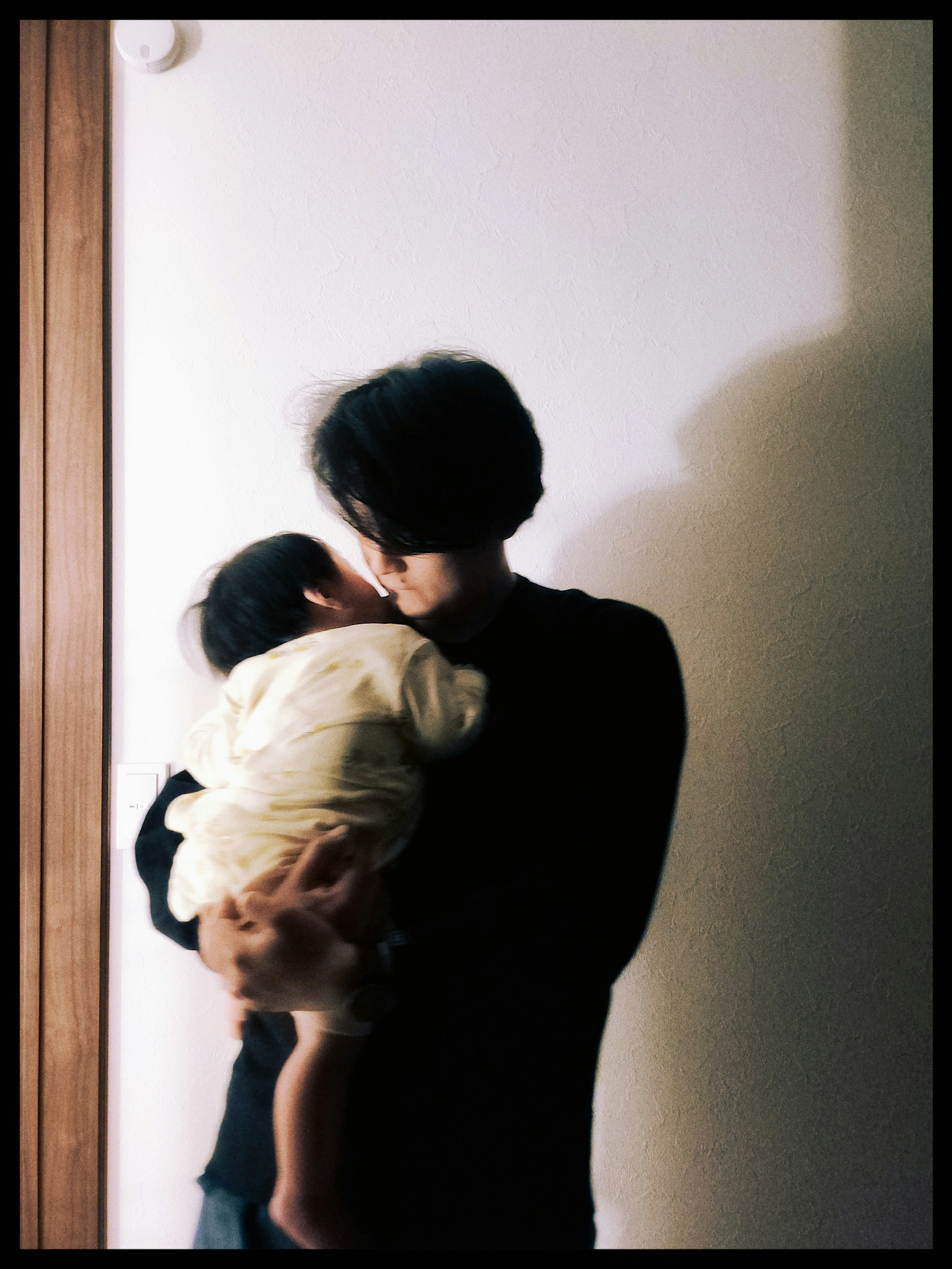 Silhouette of a parent holding a child in a dimly lit room