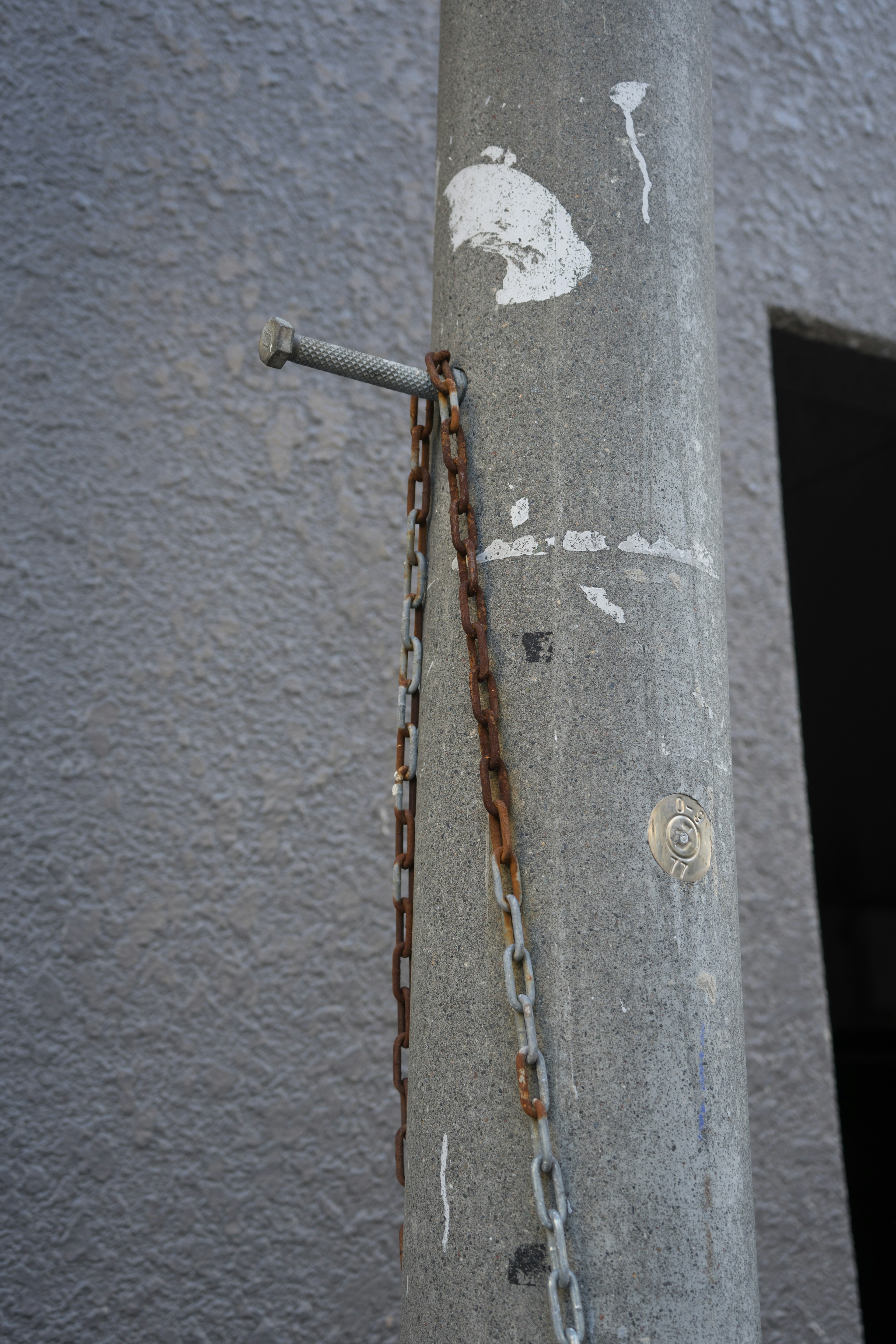 Primo piano di una catena arrugginita su un palo di cemento