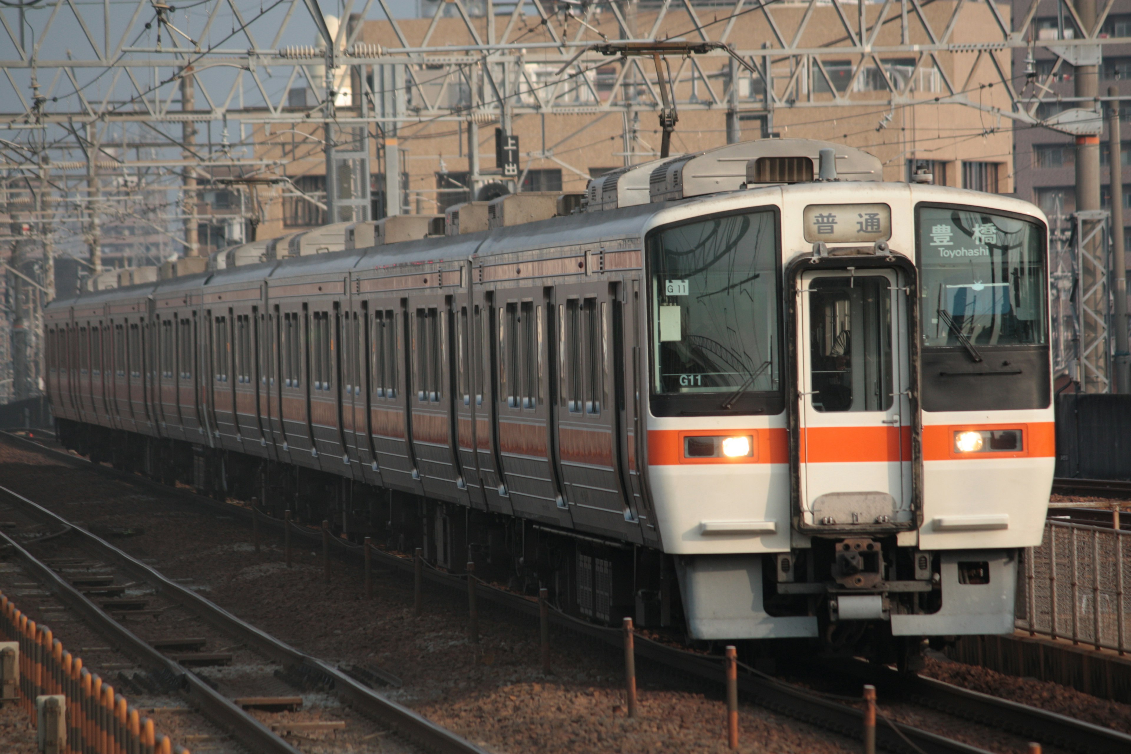 オレンジと白のストライプが特徴の日本の電車が線路を走っている