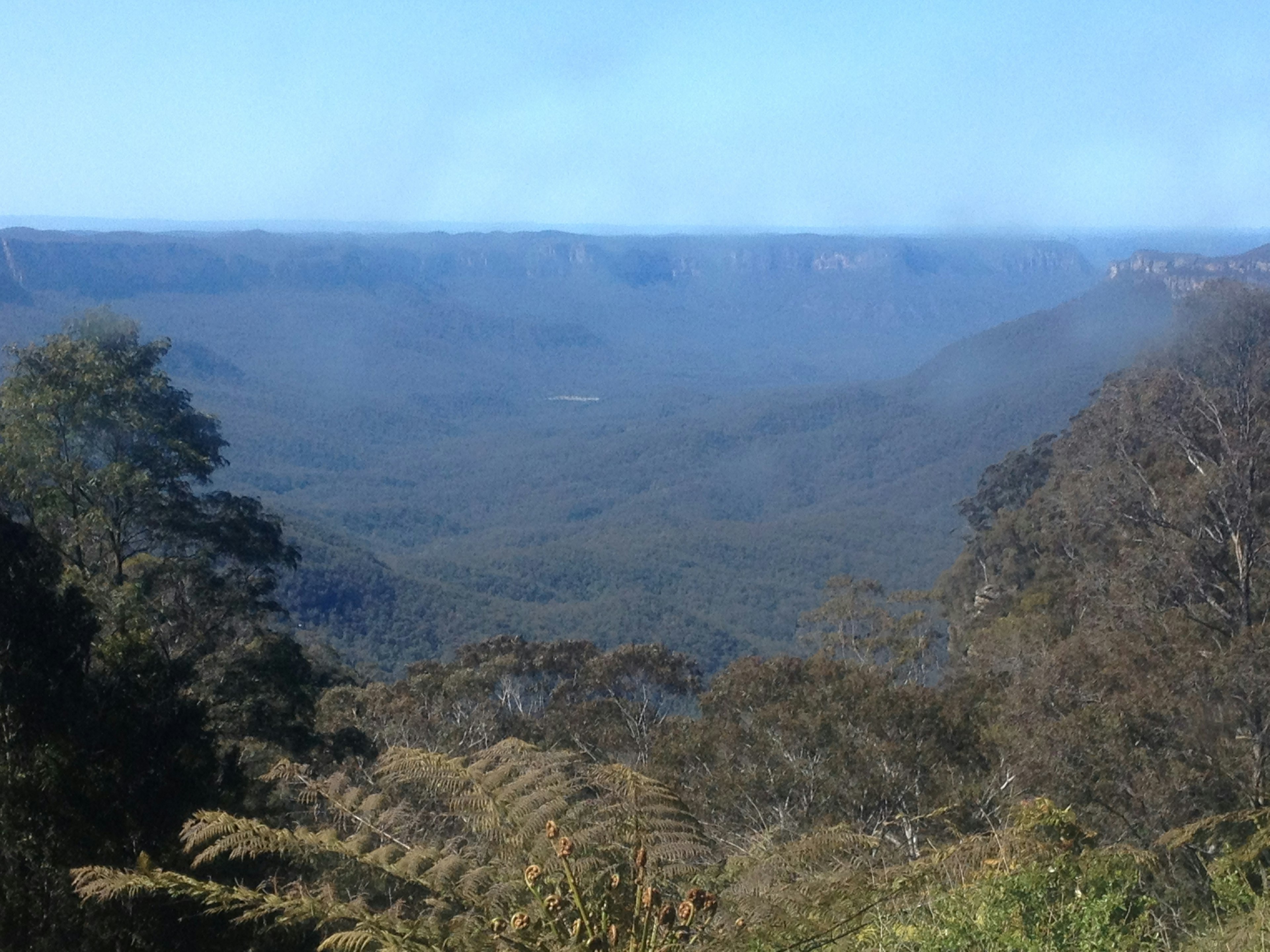 Amplio paisaje de valle montañosa con cielo azul y niebla