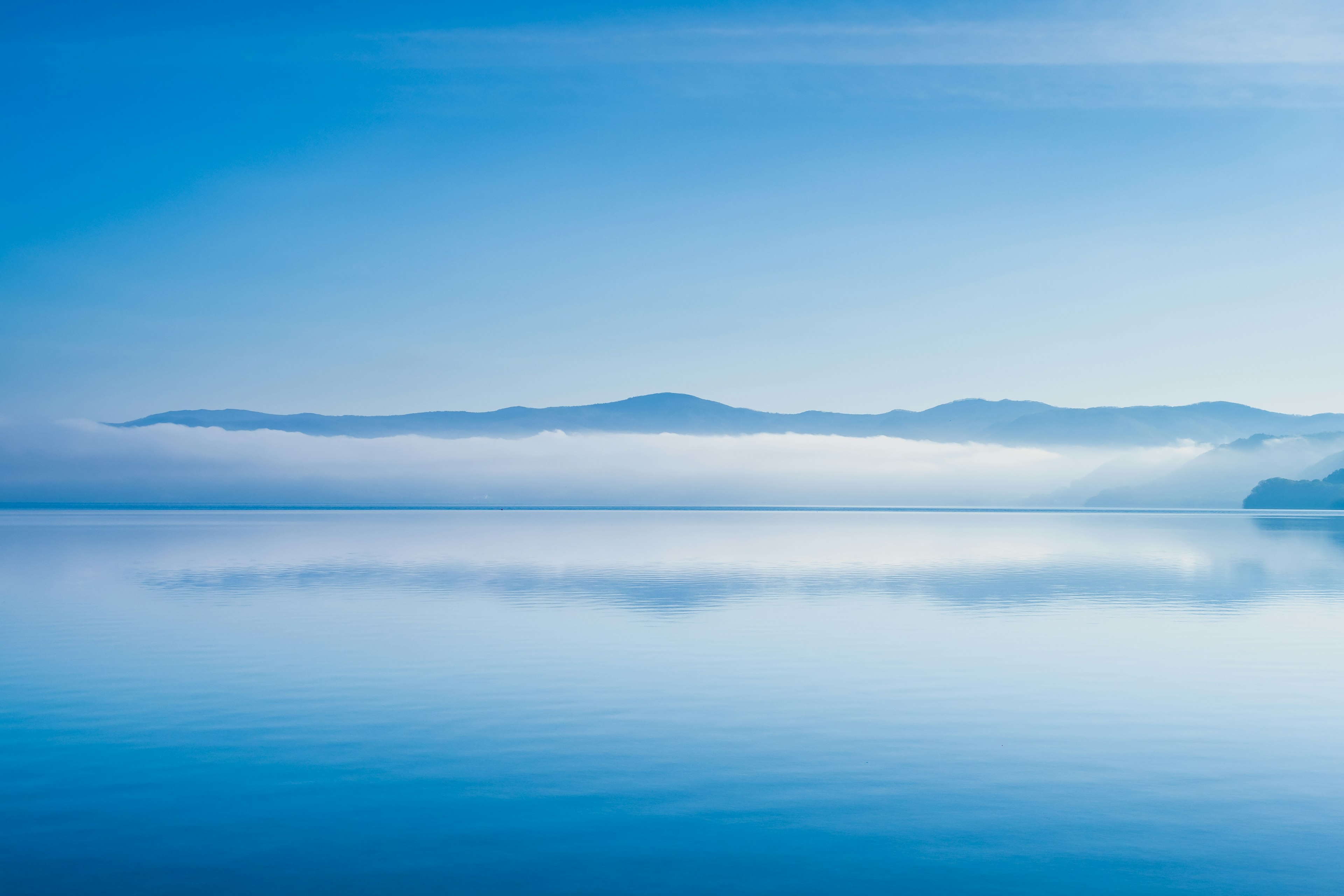 Superficie calma del lago blu con montagne lontane