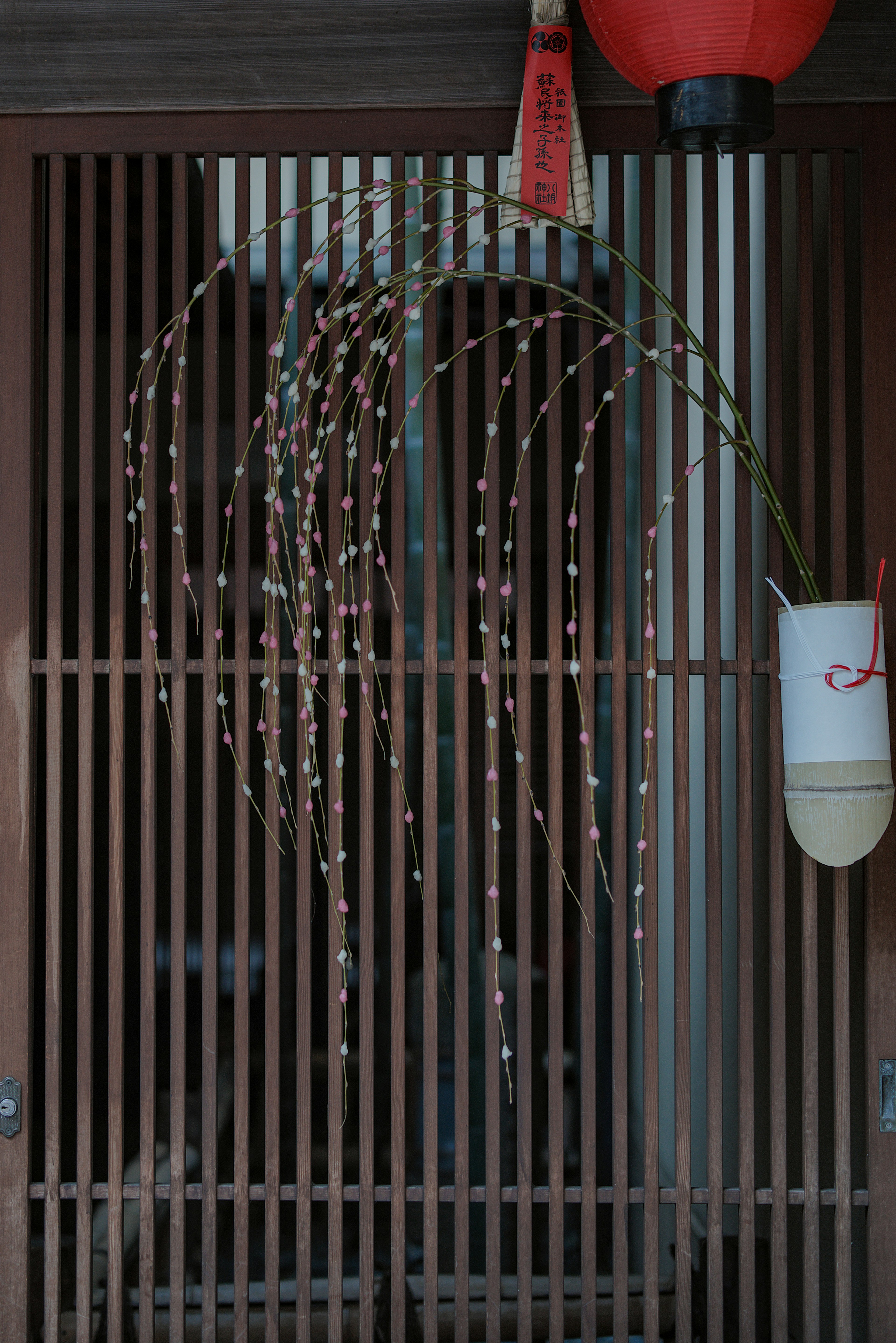 Branches de bambou ornées sur une porte à lattes en bois avec une lanterne rouge