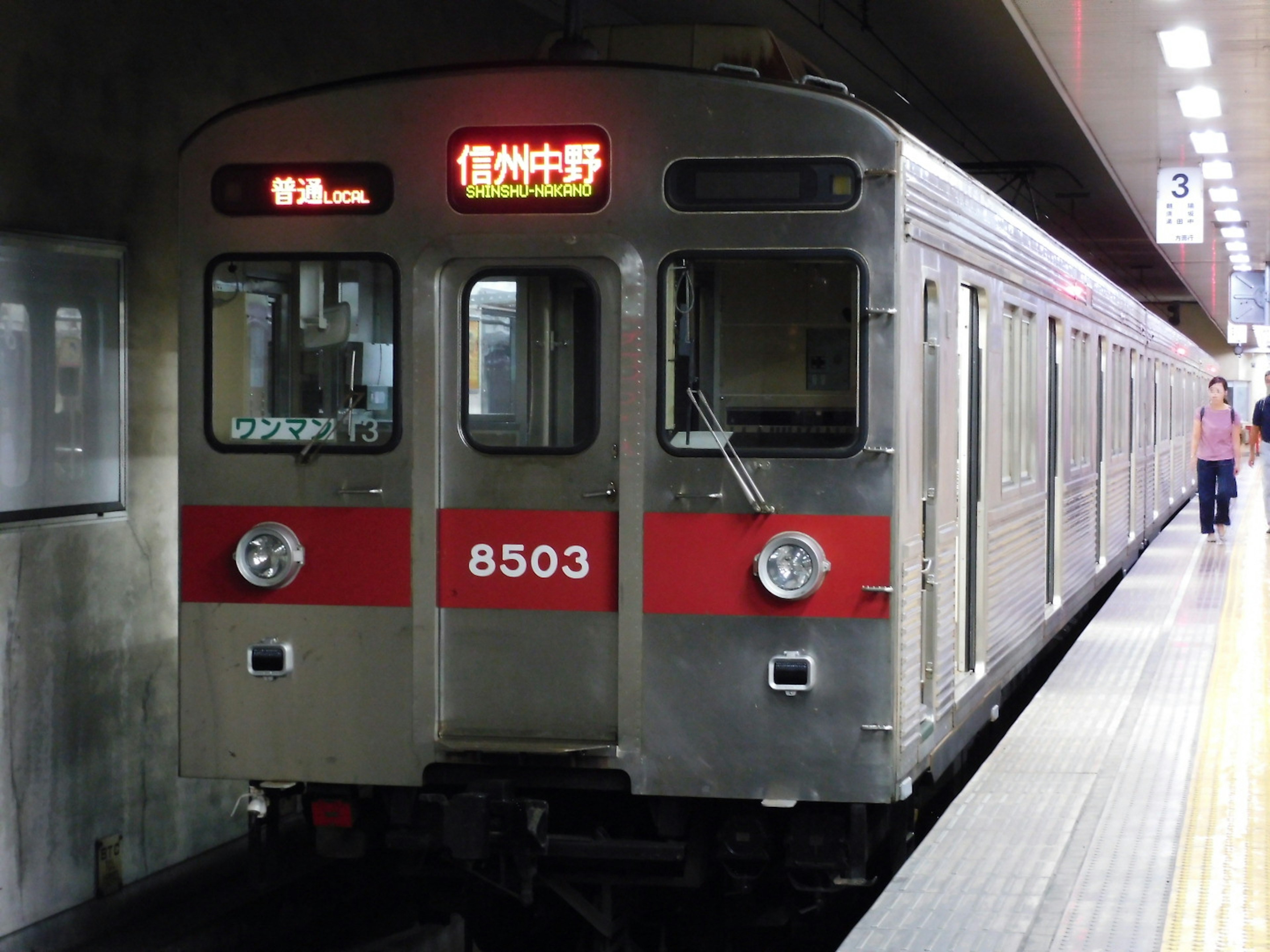 Silver subway train with red stripes at a station