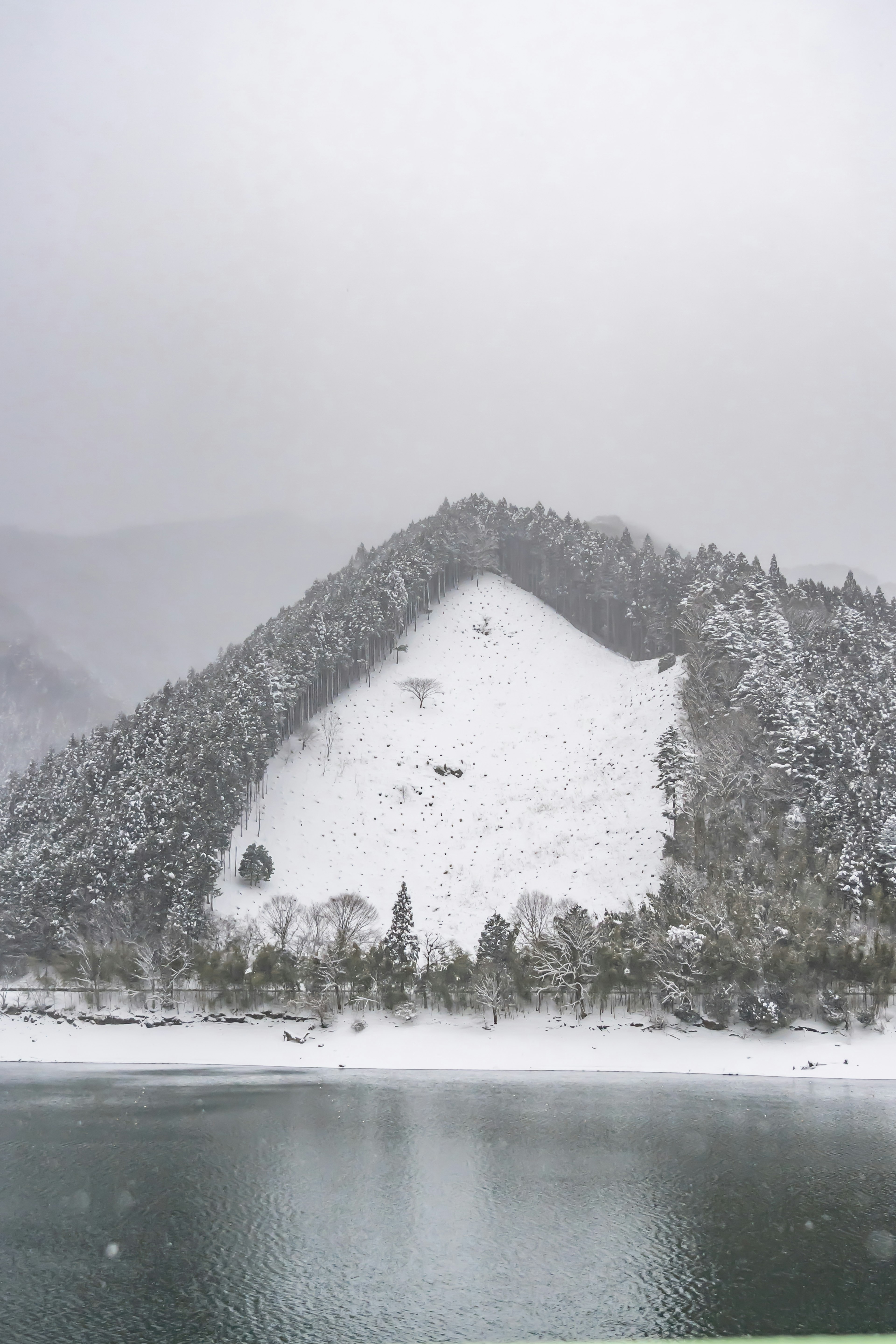 Montagna coperta di neve con vista su un lago sereno