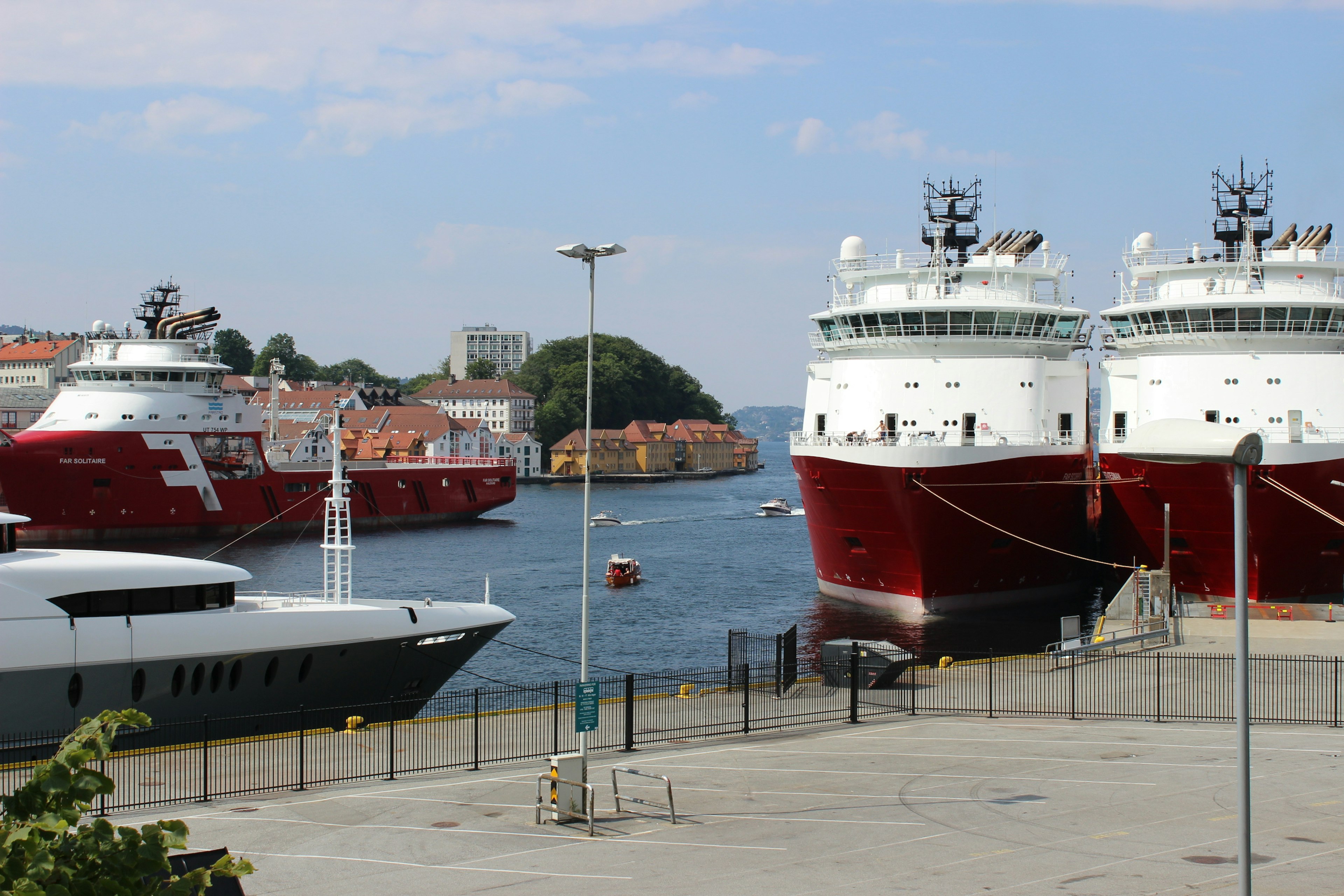 View of red boats docked in the harbor with a yacht