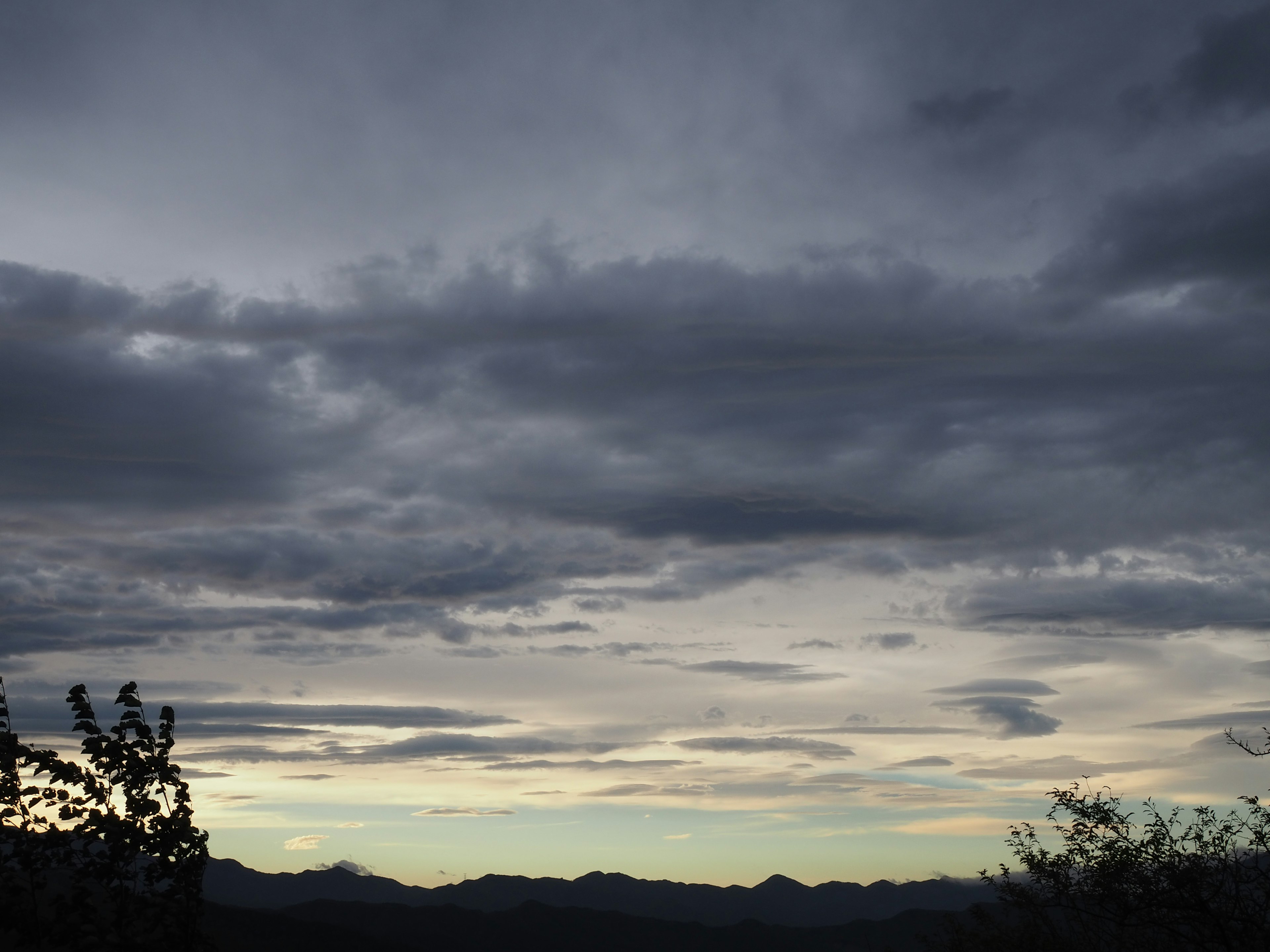 Dark clouds covering the sky with silhouettes of distant mountains