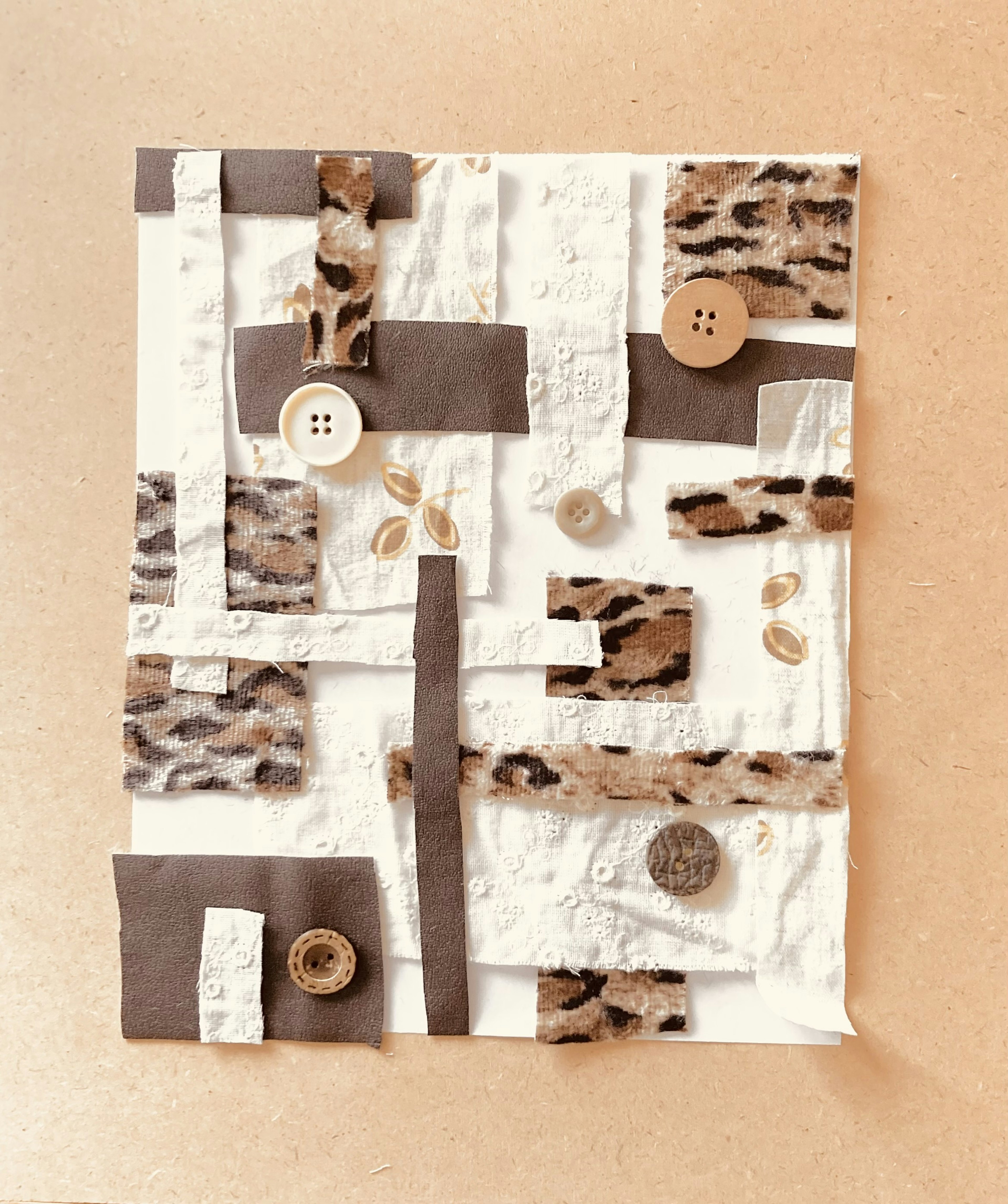 Collage artwork featuring white and brown textures with buttons and layered materials