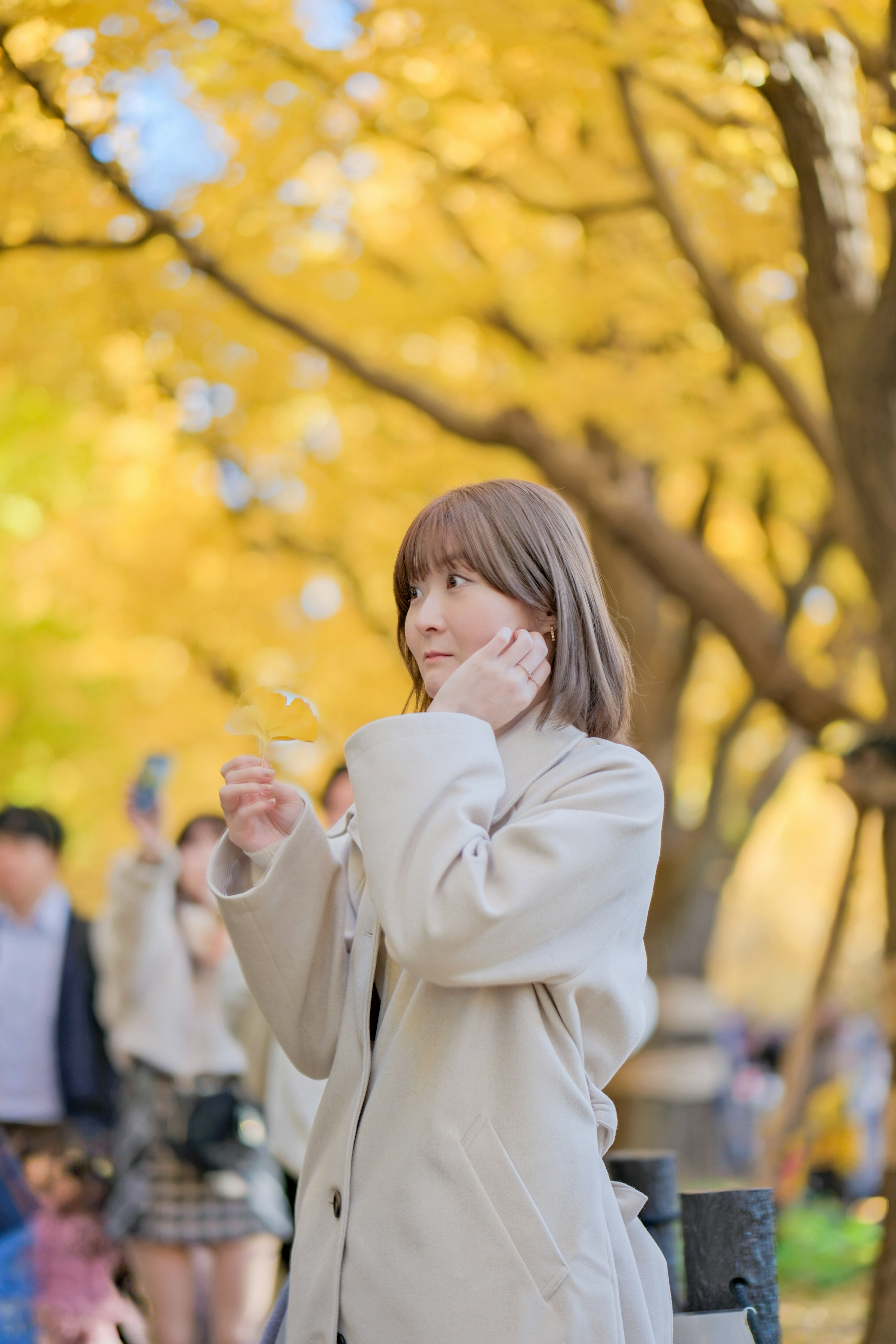 秋の公園で黄色い葉の中に立つ女性