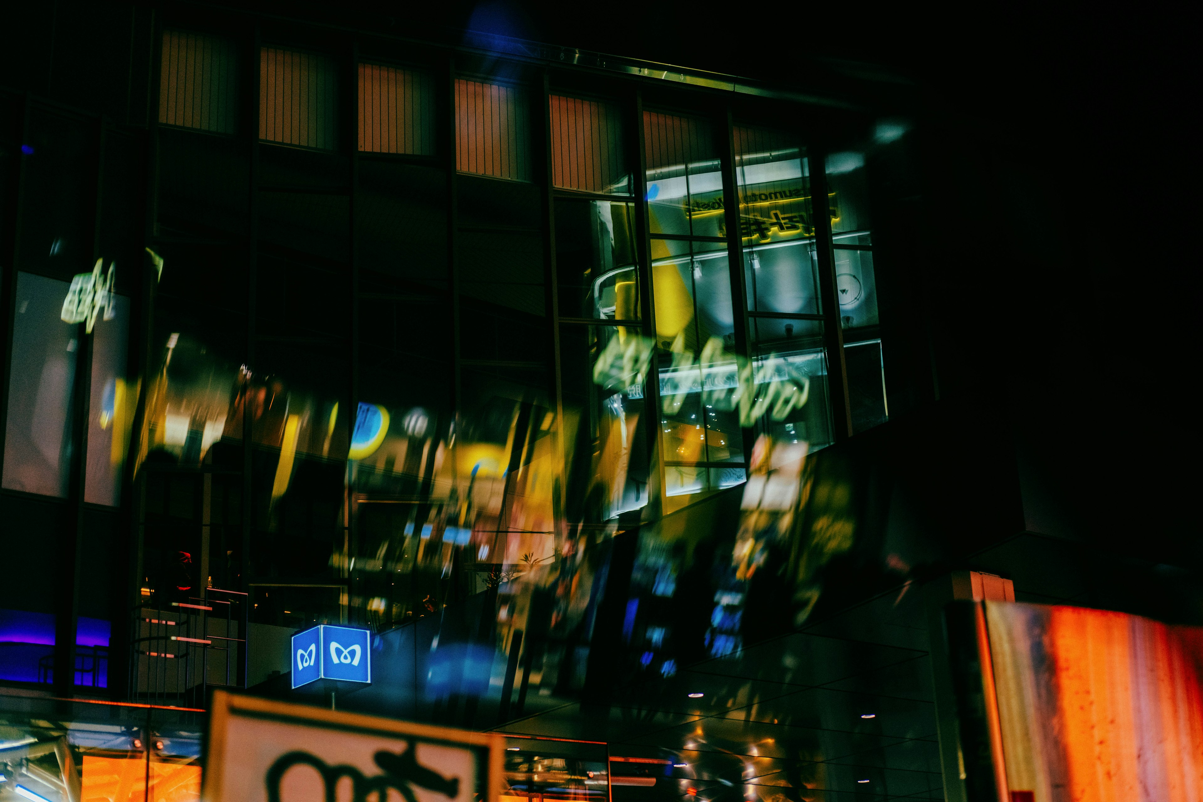 Fachada de edificio reflejando luces de la ciudad de noche