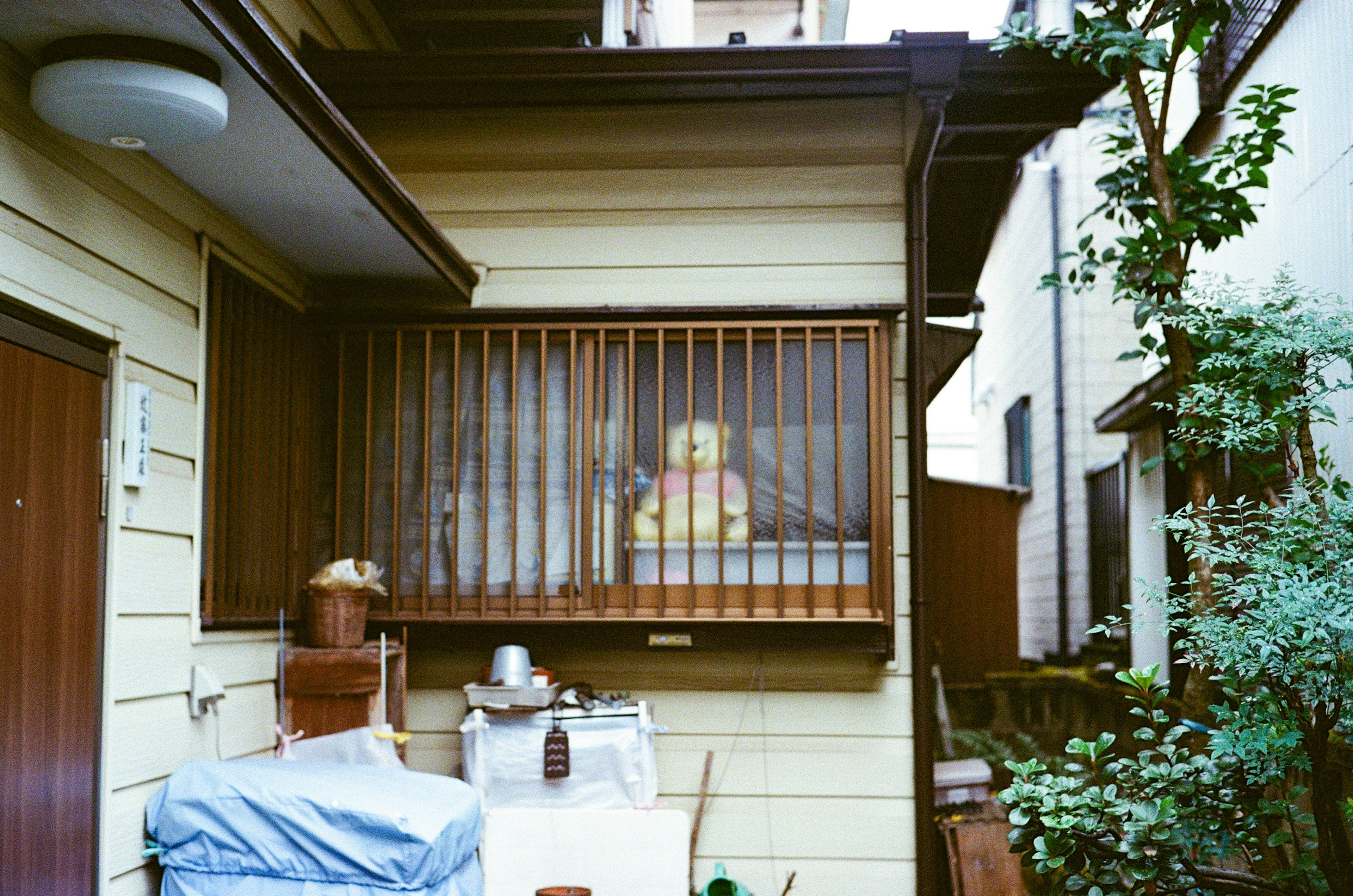 Exterior of a Japanese house featuring a yellow doll visible through window bars