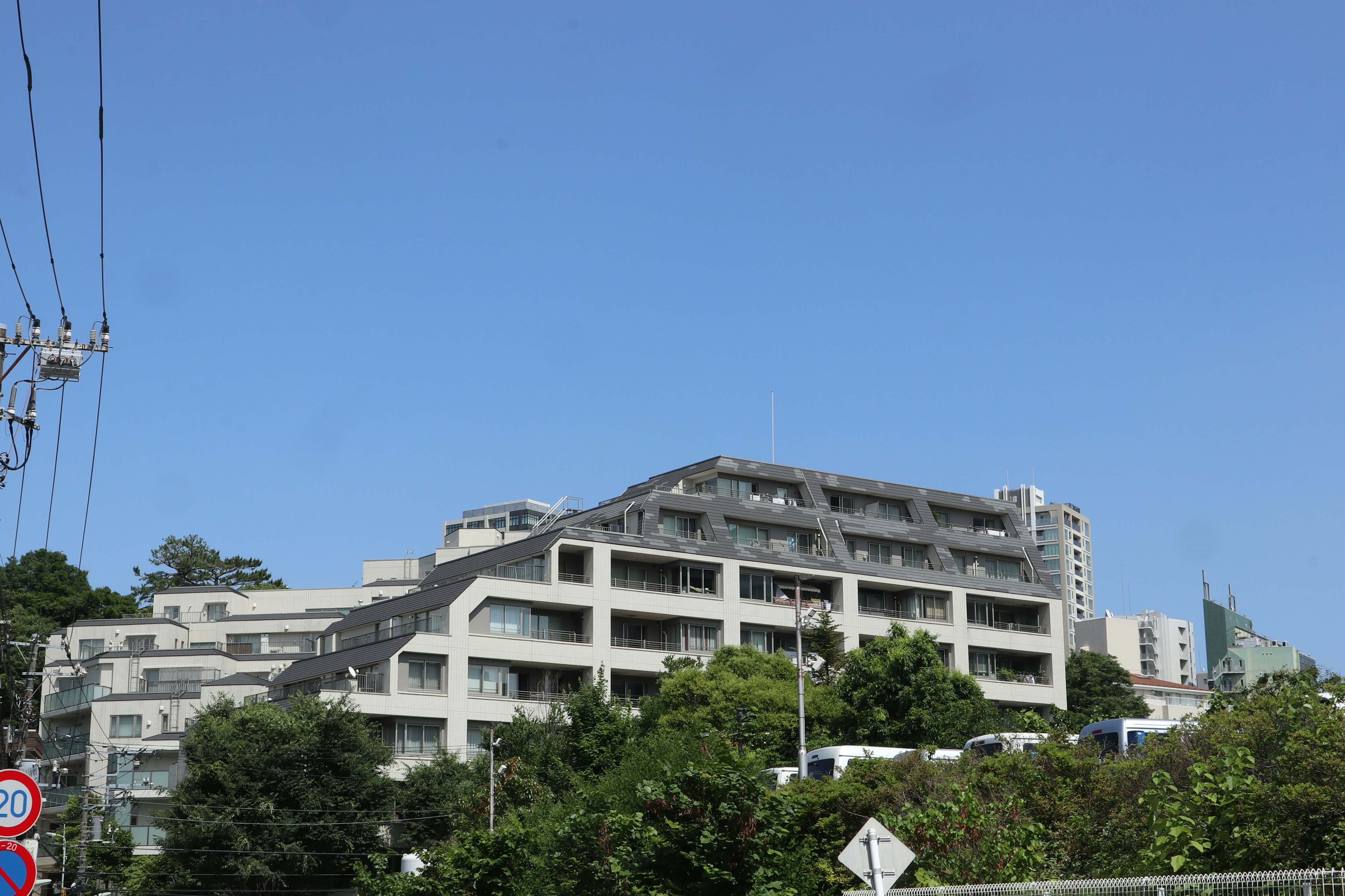 Modern building under a clear blue sky with greenery