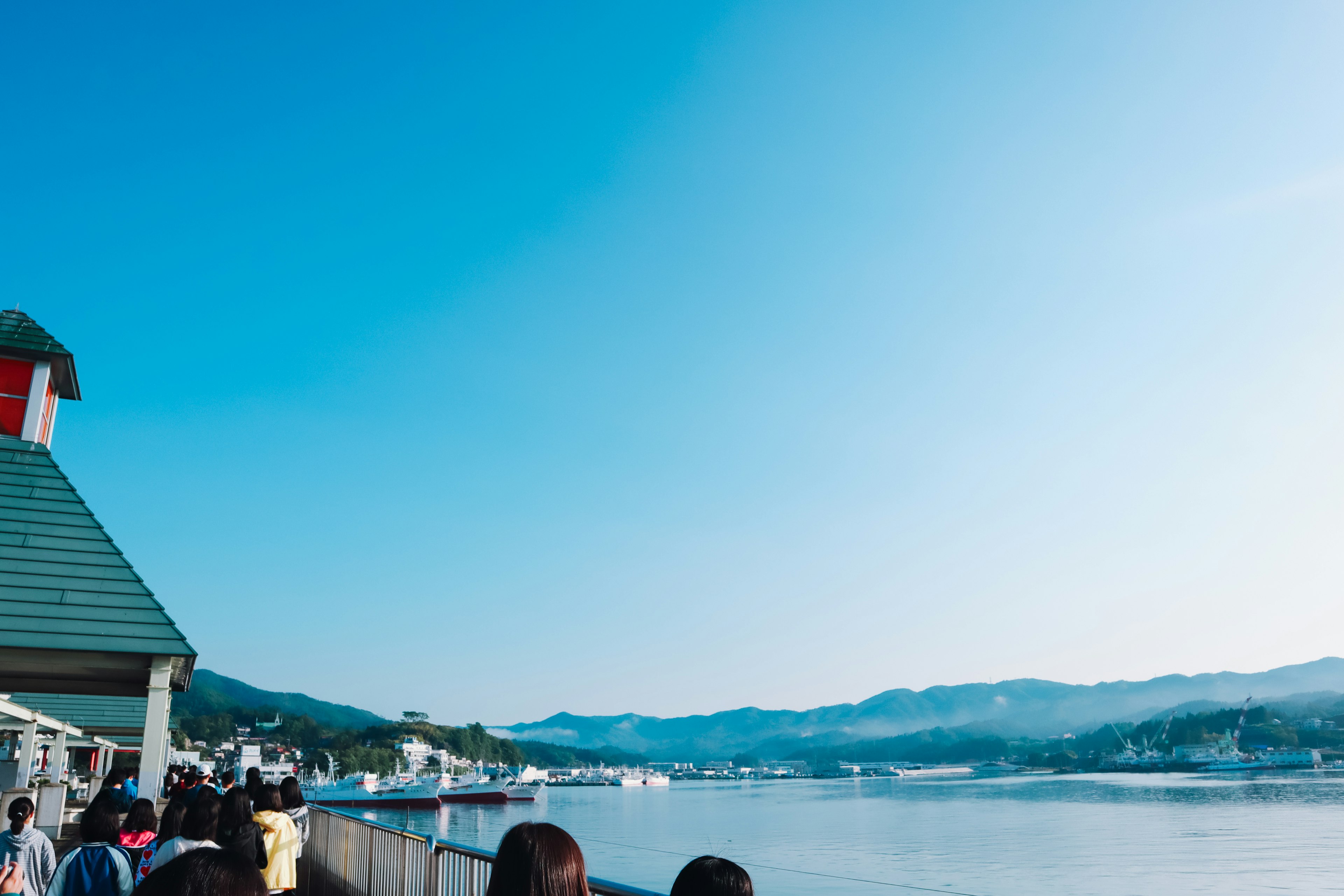 青空の下で川沿いを歩く人々の風景