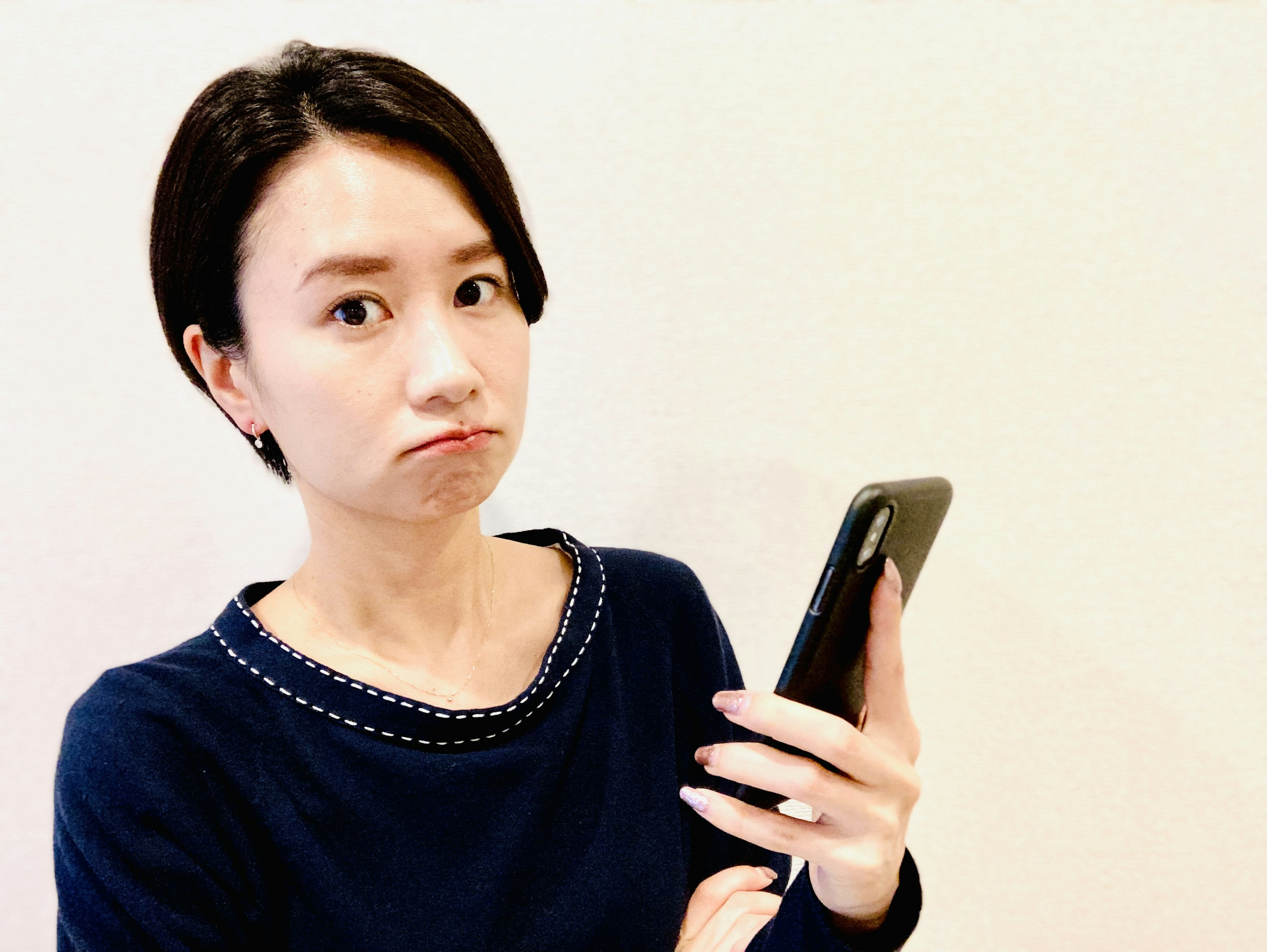 スマートフォンを持つ女性が困惑した表情をしています