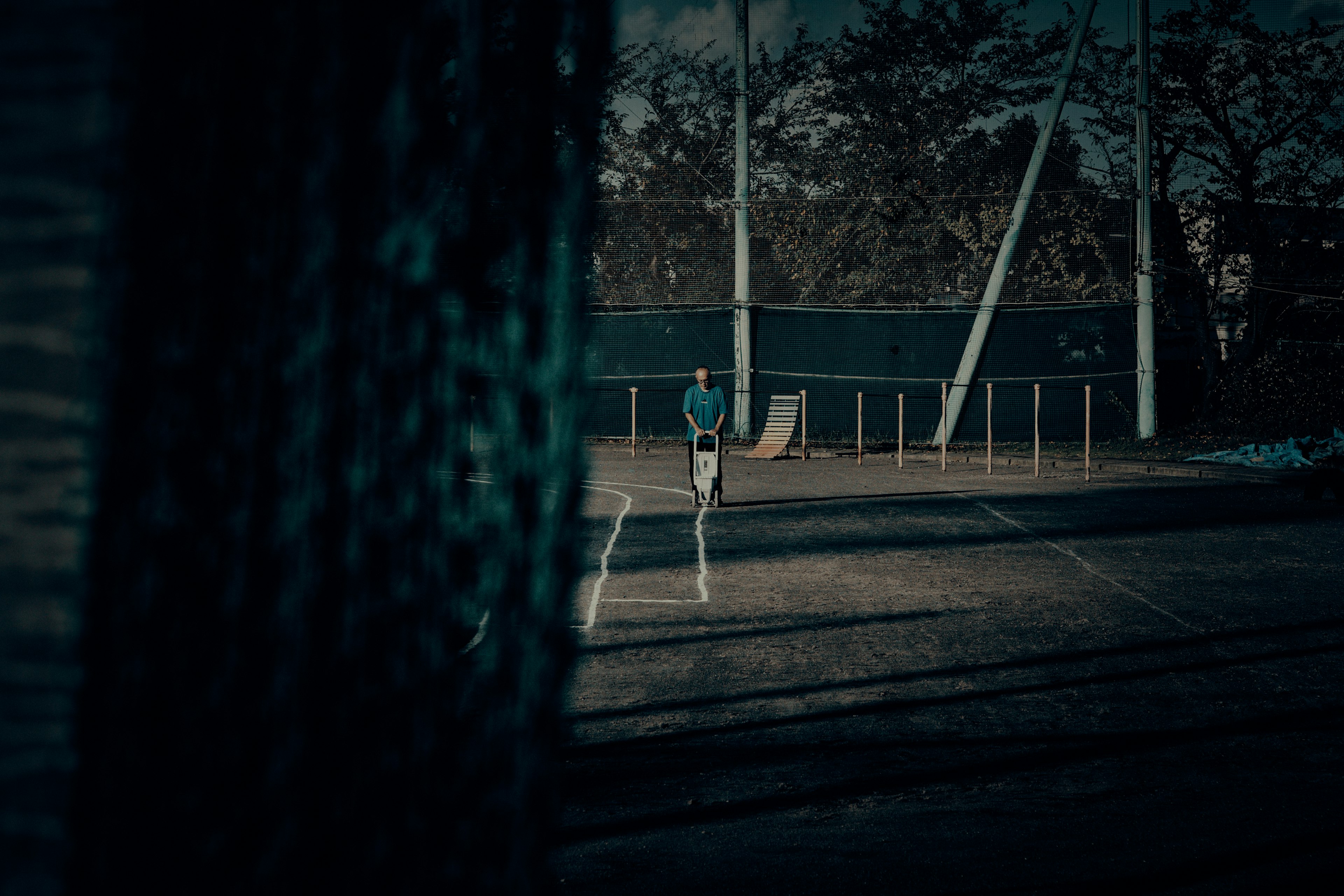 Silhouette of a player standing on a dimly lit tennis court