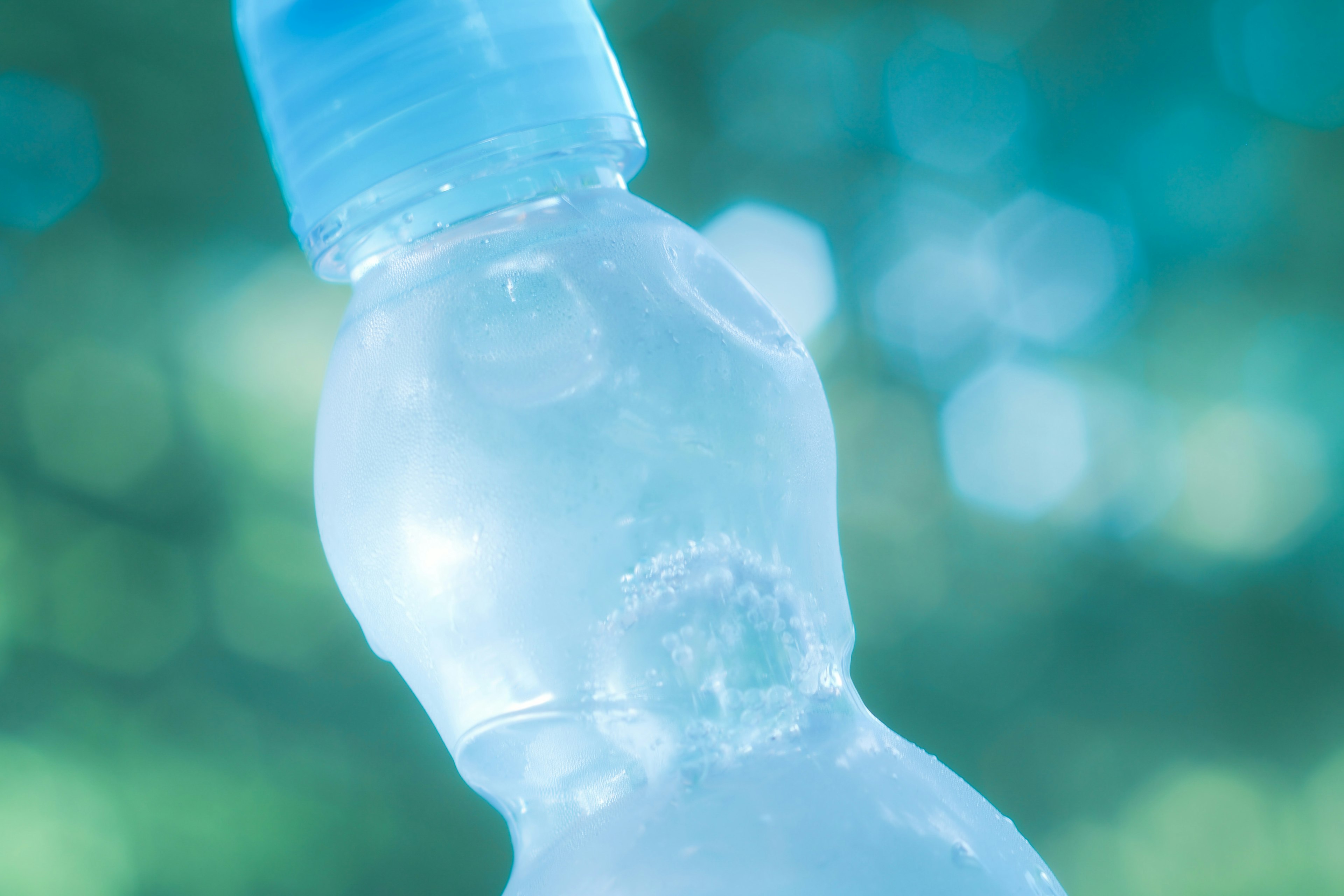 Sebuah botol air dengan permukaan berkilau di latar belakang biru