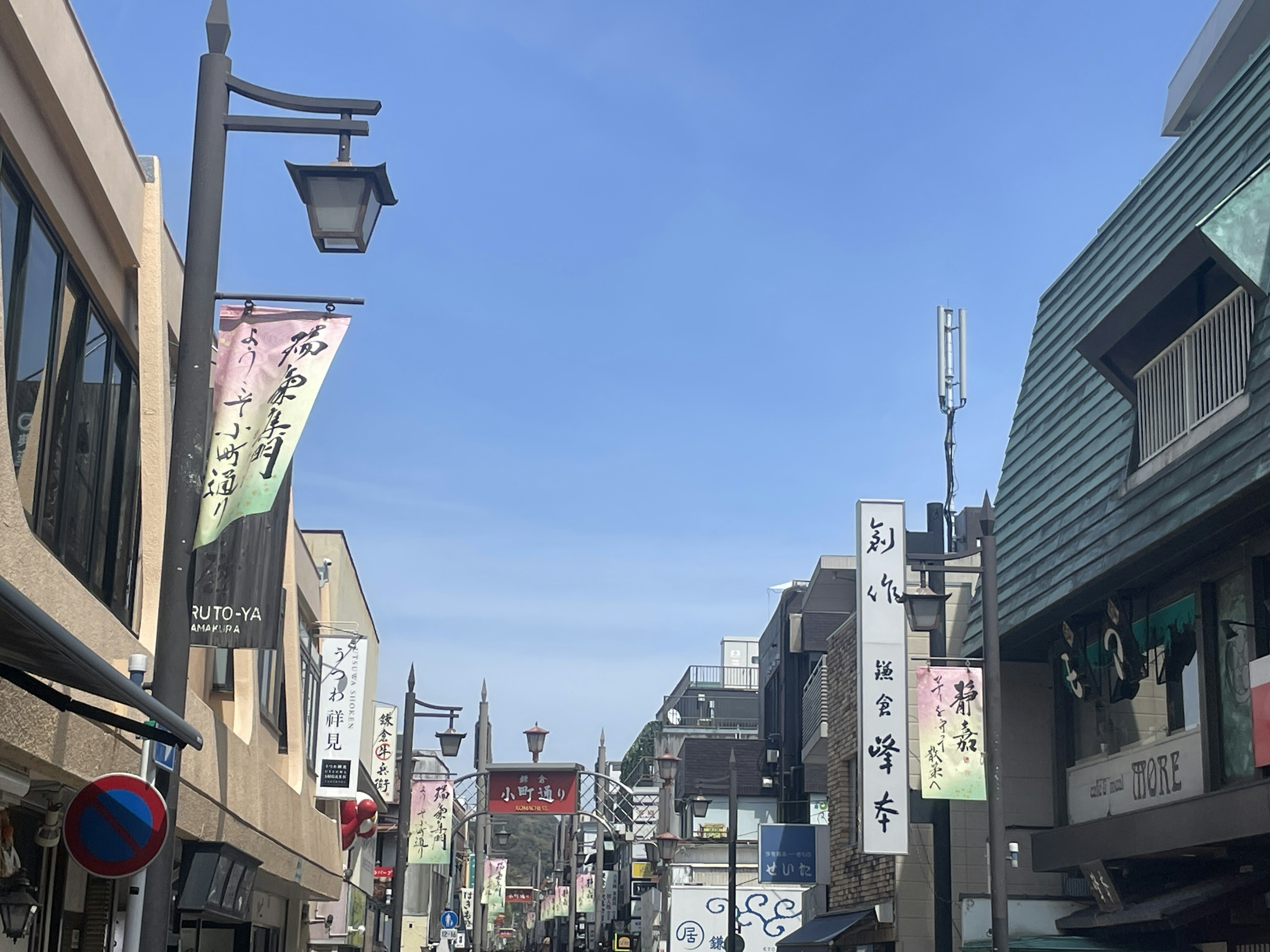 Lebendige Einkaufsstraße unter blauem Himmel mit Laternen an Laternenmasten