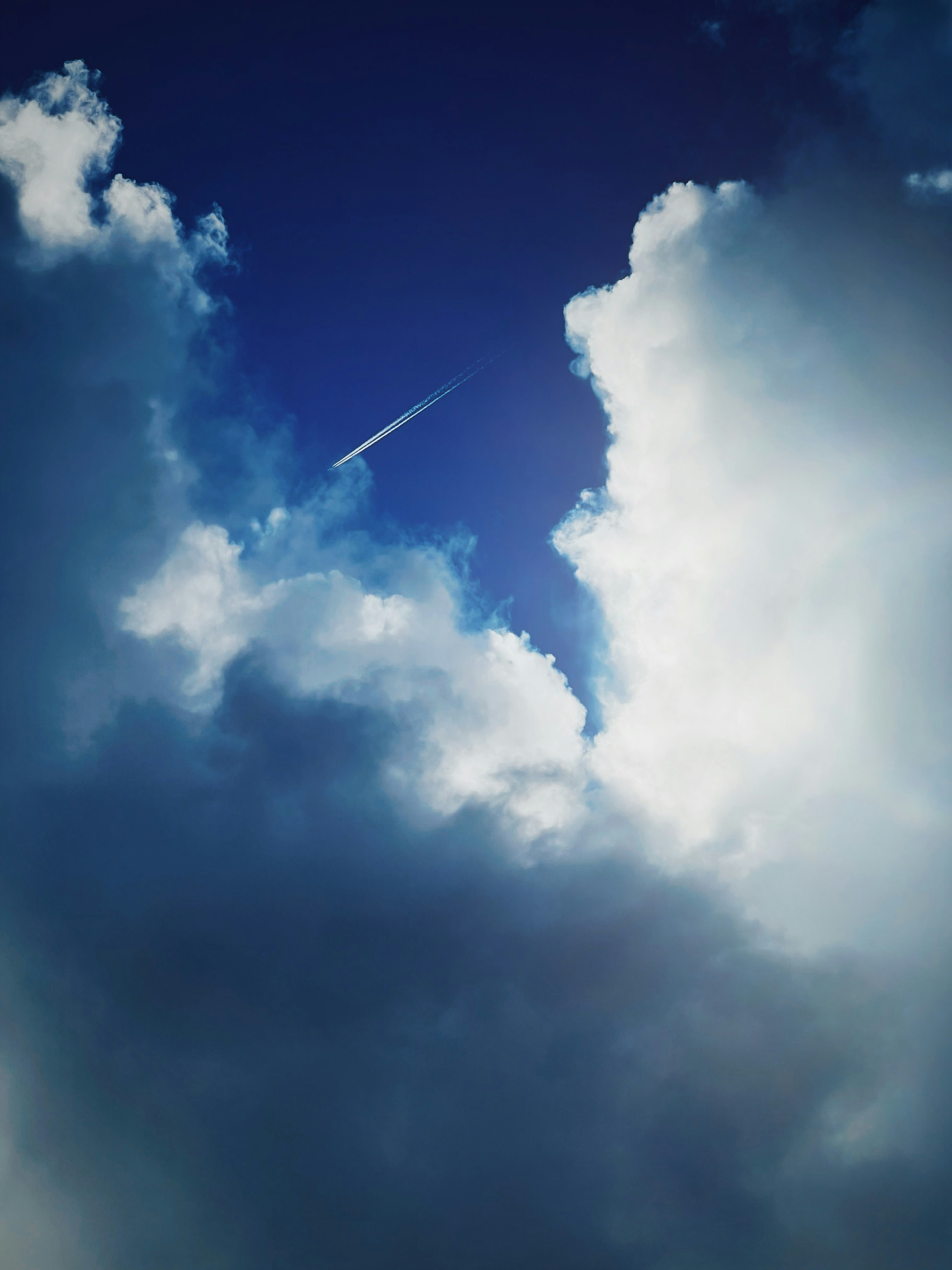 Blauer Himmel mit weißen Wolken und sichtbarem Kondensstreifen