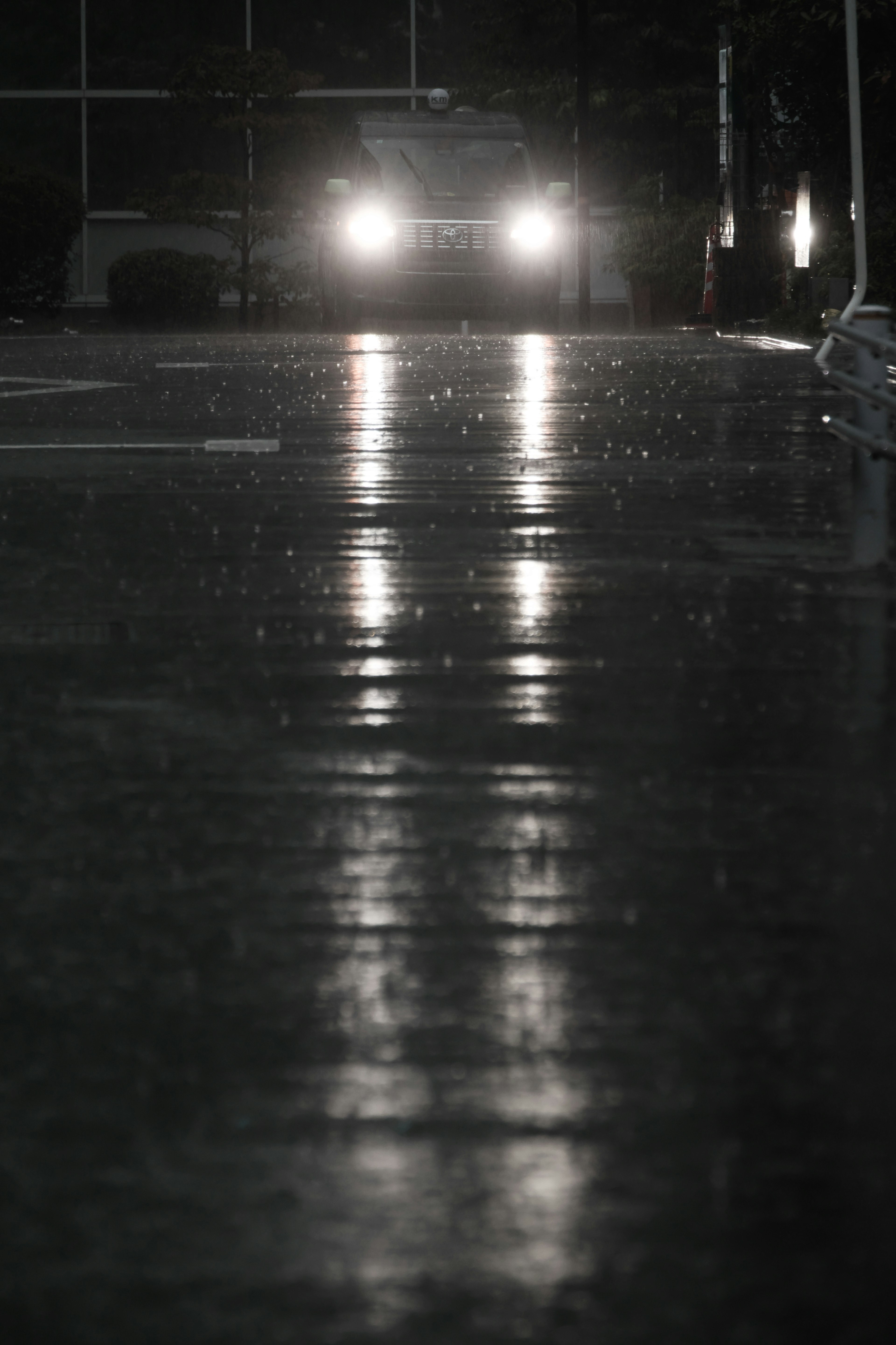 濕滑的道路反射著汽車大燈的光芒，正值雨中