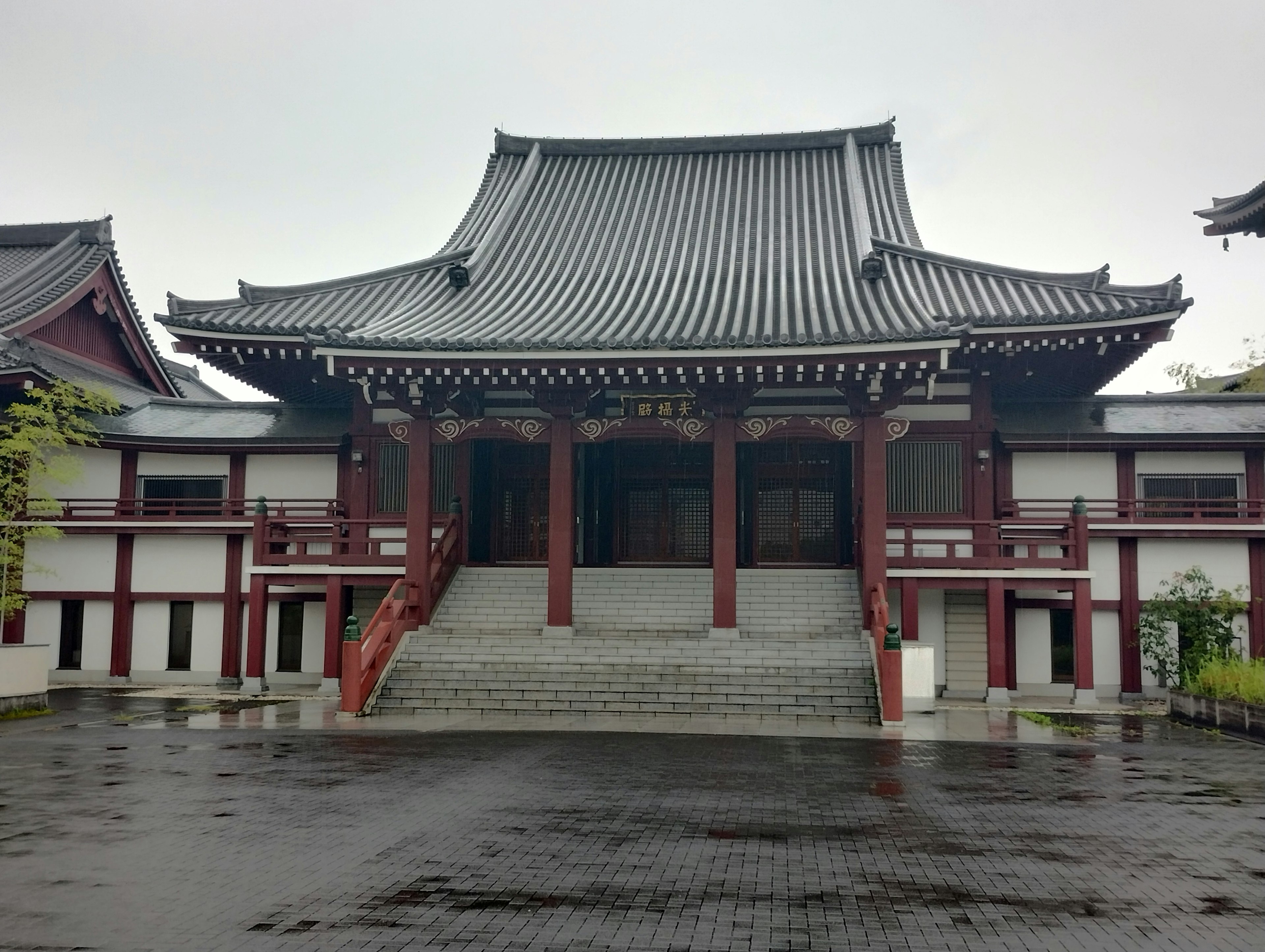 Front entrance of a traditional Japanese temple with distinctive architecture in a tranquil rainy setting