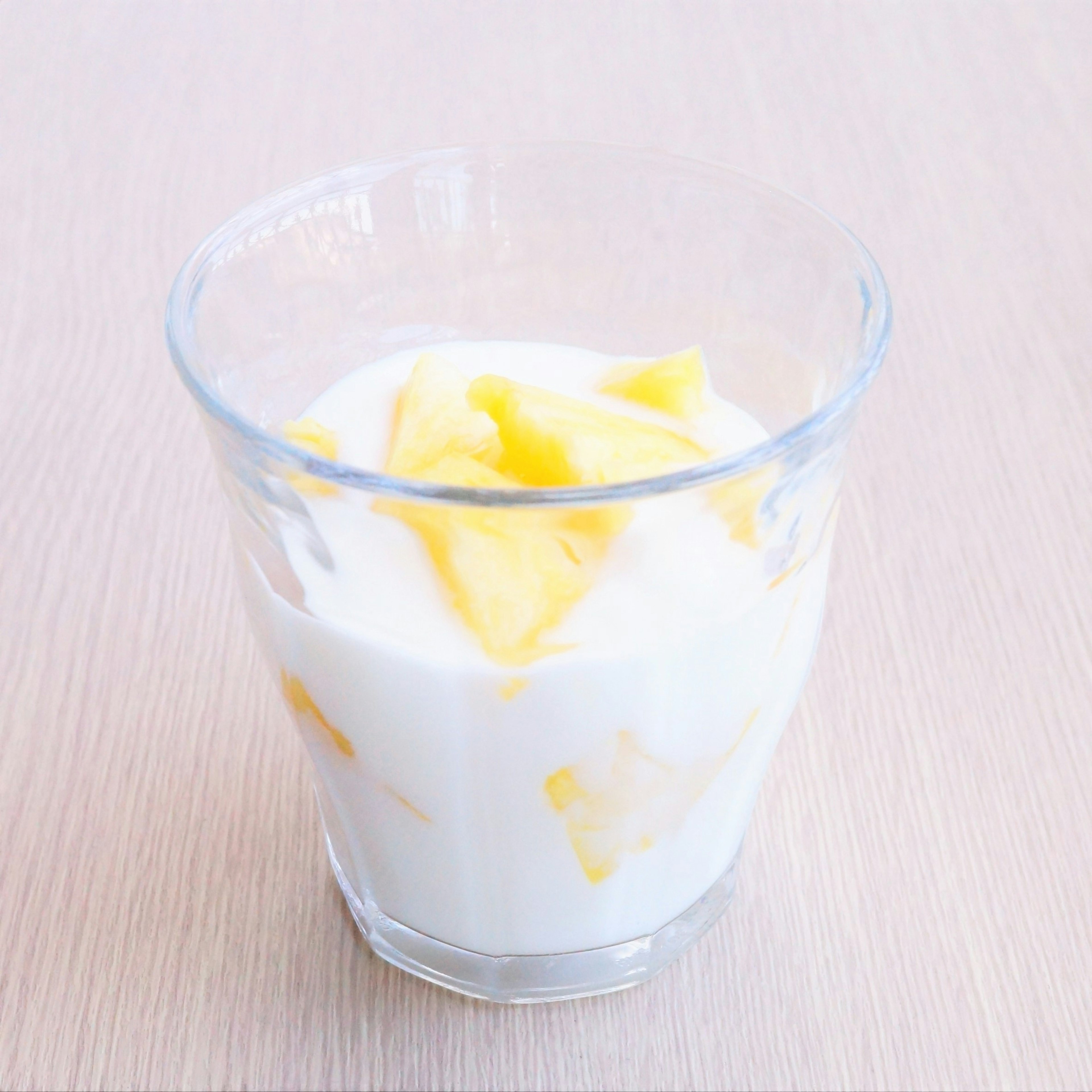 Postre en un vaso transparente con yogur y trozos de mango